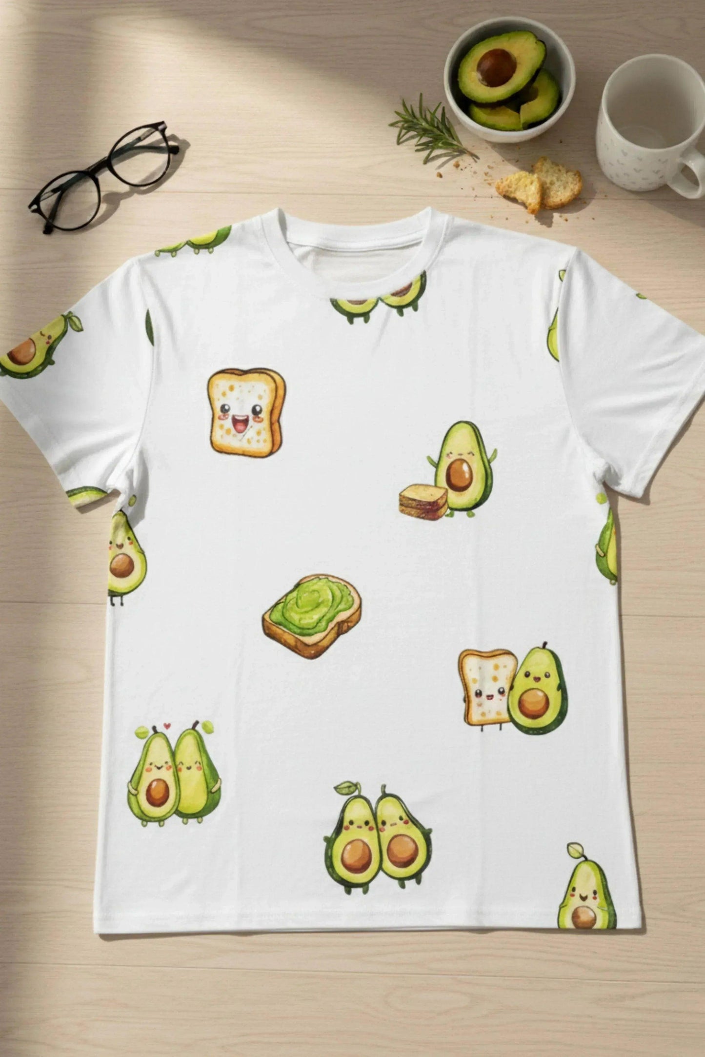 Light green t-shirt with avocado and toast illustrations on a wooden surface.