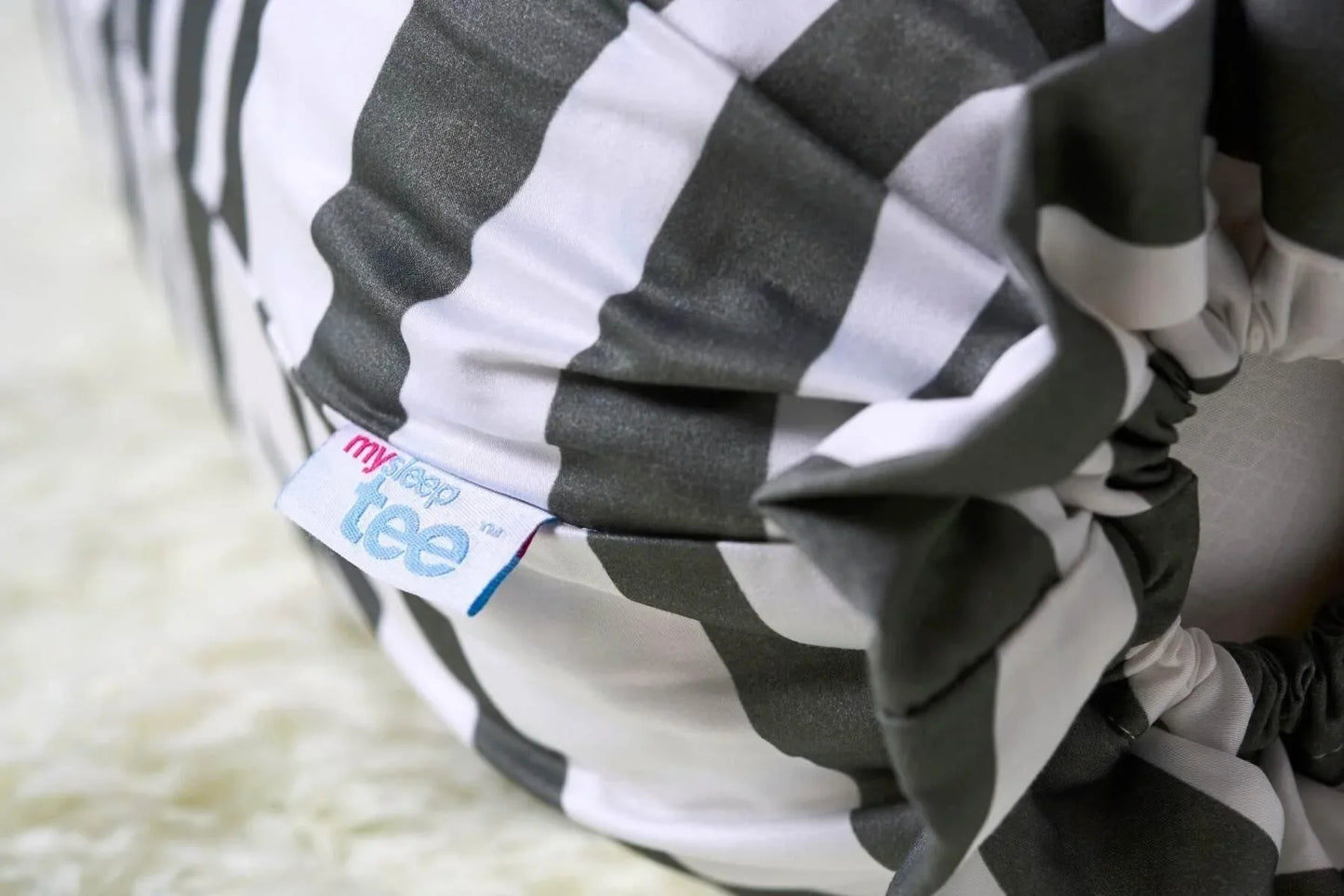 Black and white striped bolster close up with a visible brand tag on a light background