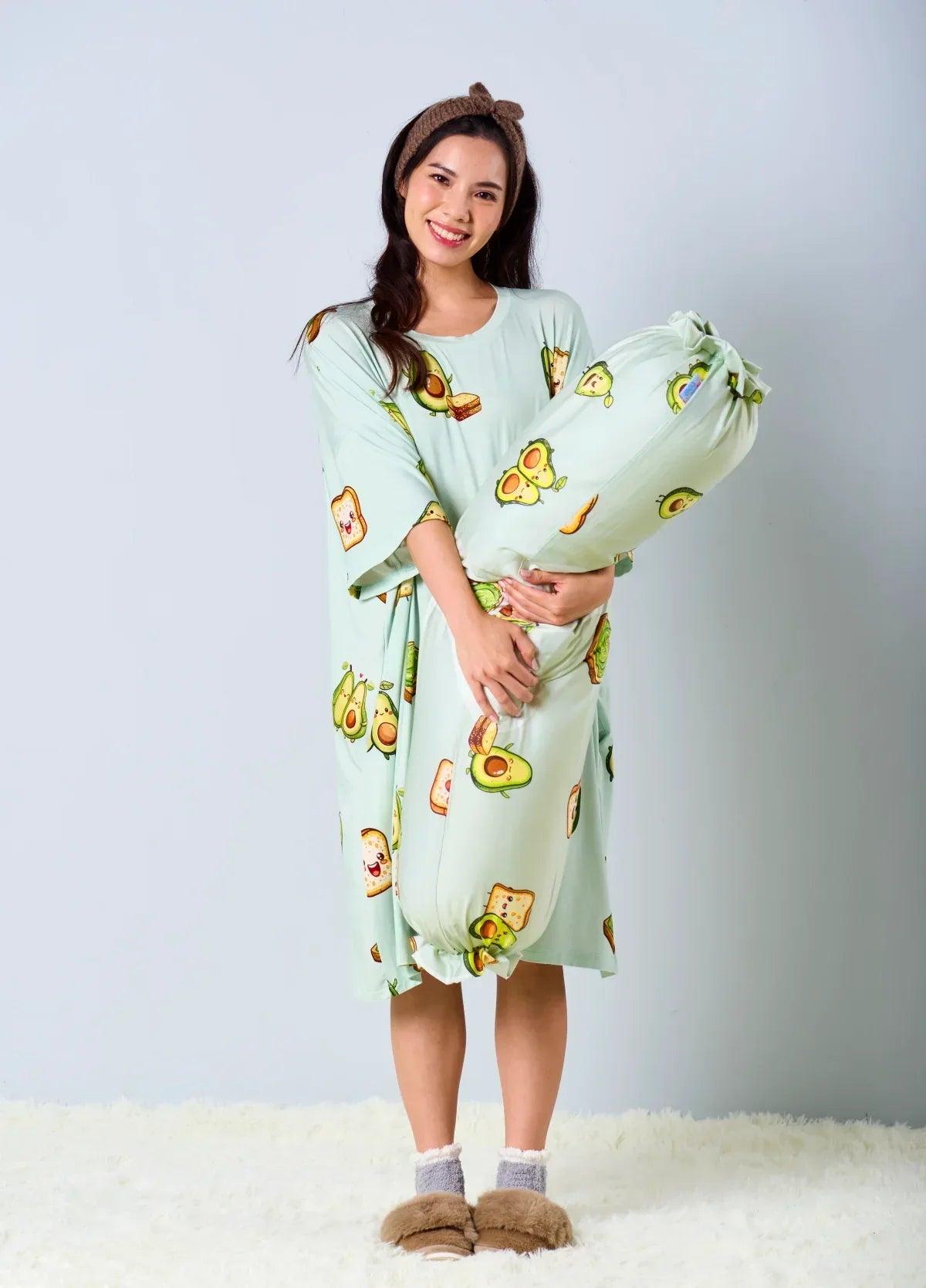 A model smiling and hugging the Avo-Good Night bolster cover while wearing a matching avocado toast print sleep dress against a light blue background.