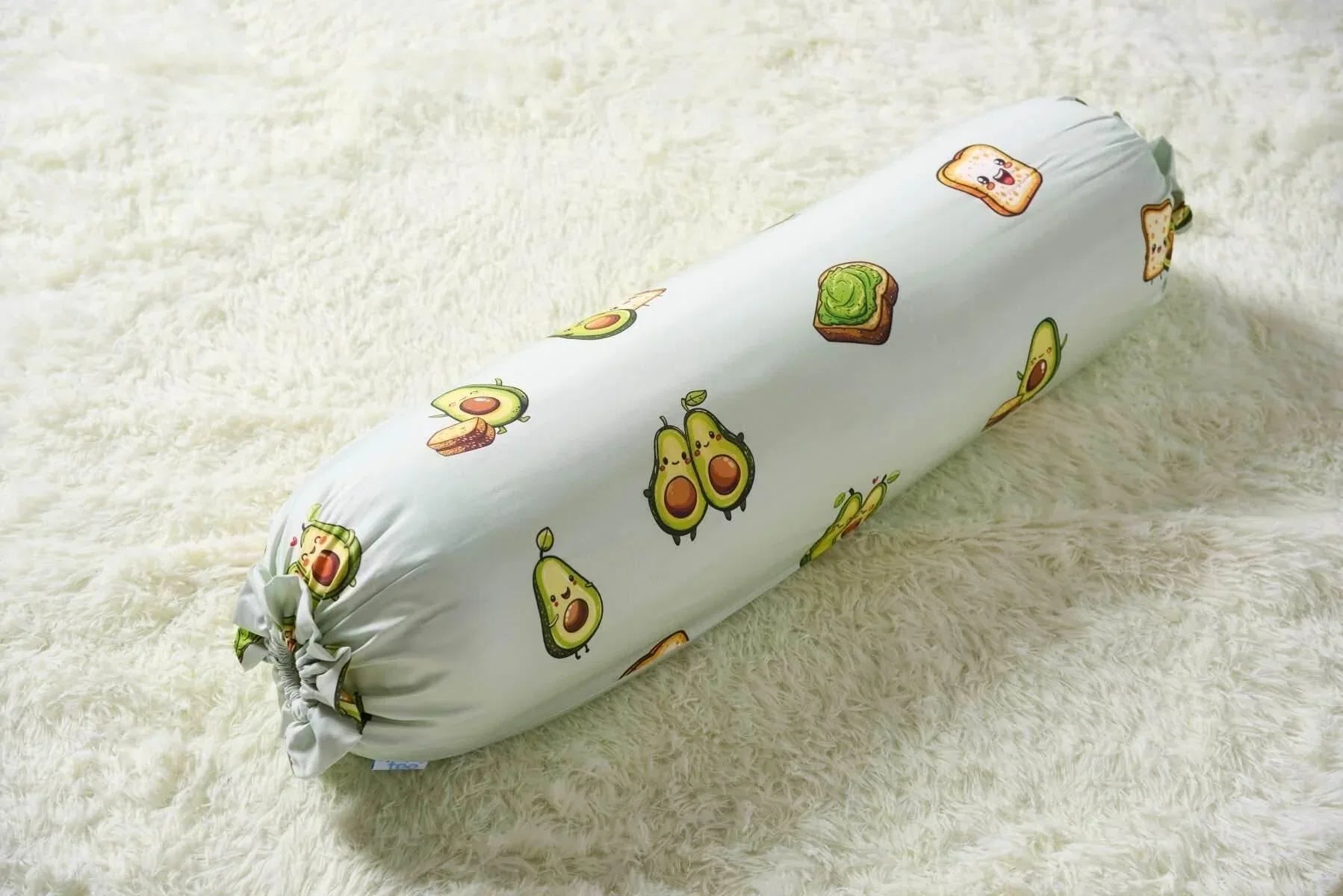 Bolster pillow with avocado pattern on a white surface