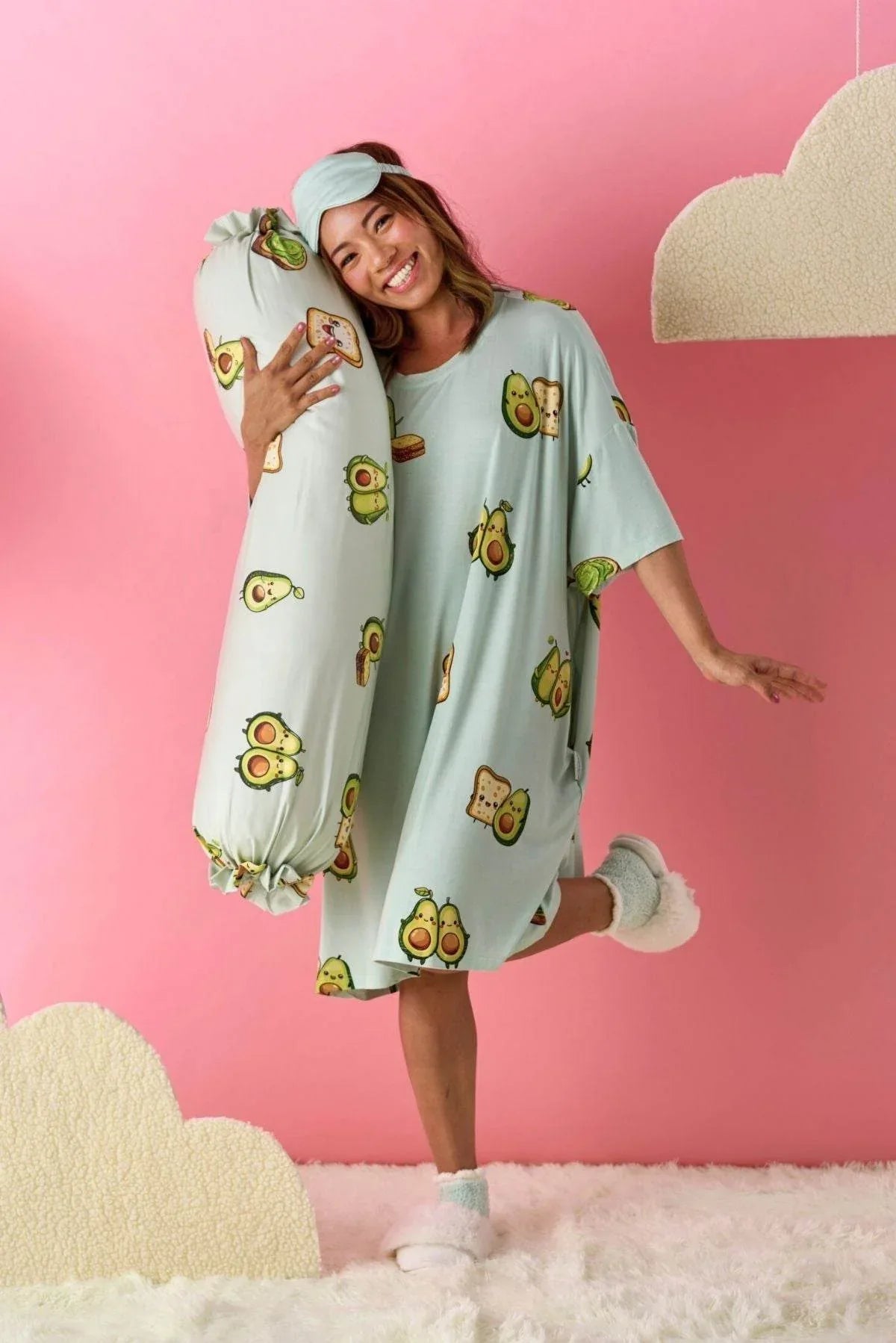 Woman wearing a light green sleep tee by MySleepTee with avocado print against a pink background