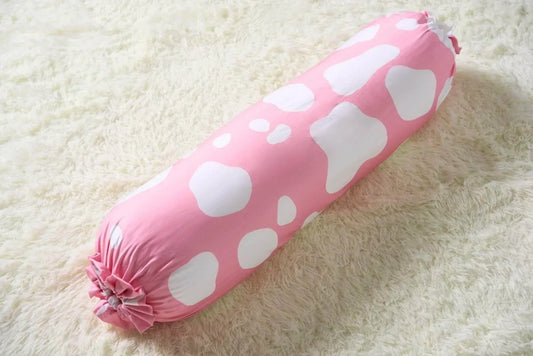 Pink bolster with white cow patterns on a light beige surface