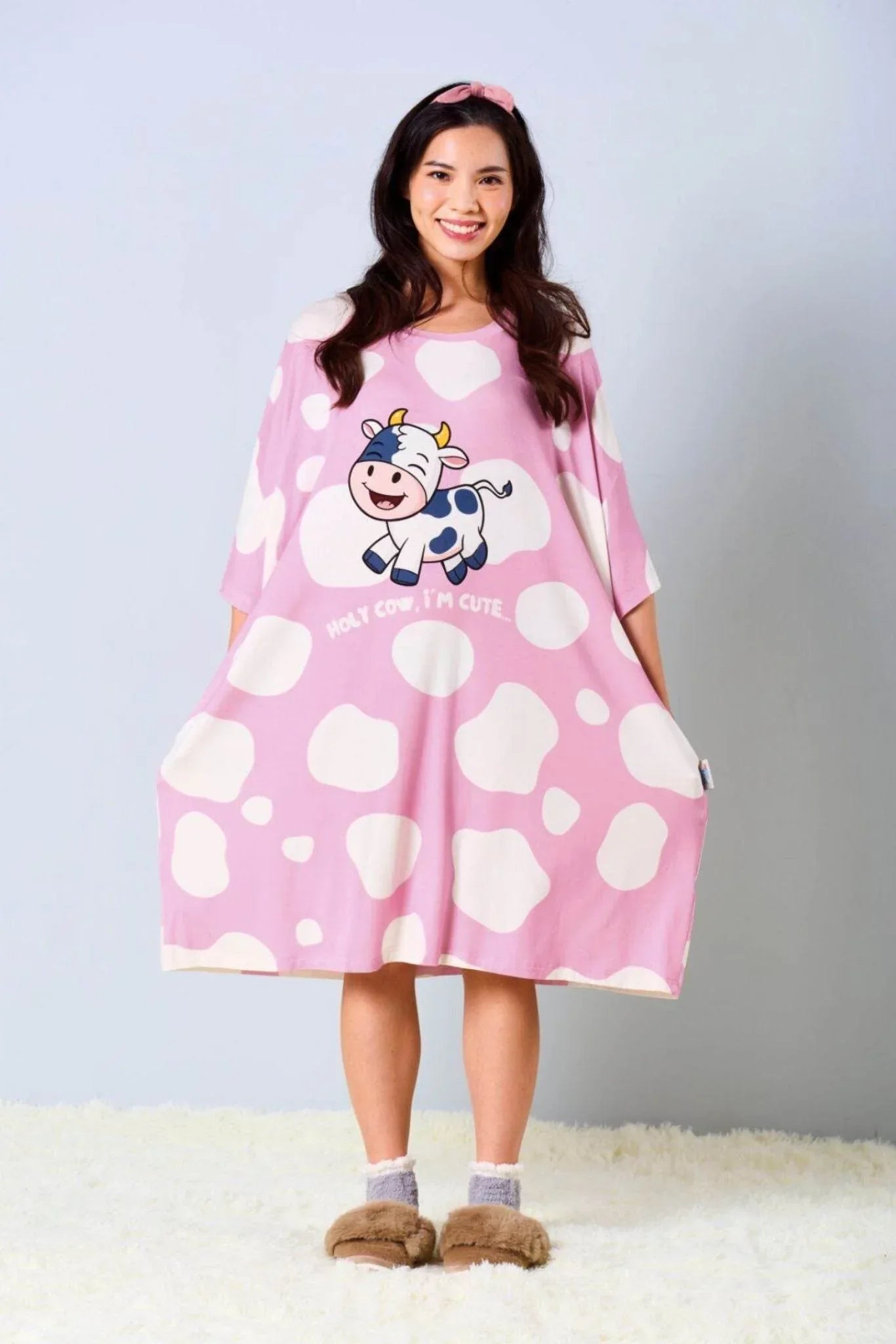 Woman wearing a pink bamboo sleep tee by mysleeptee with cow design on a plain background