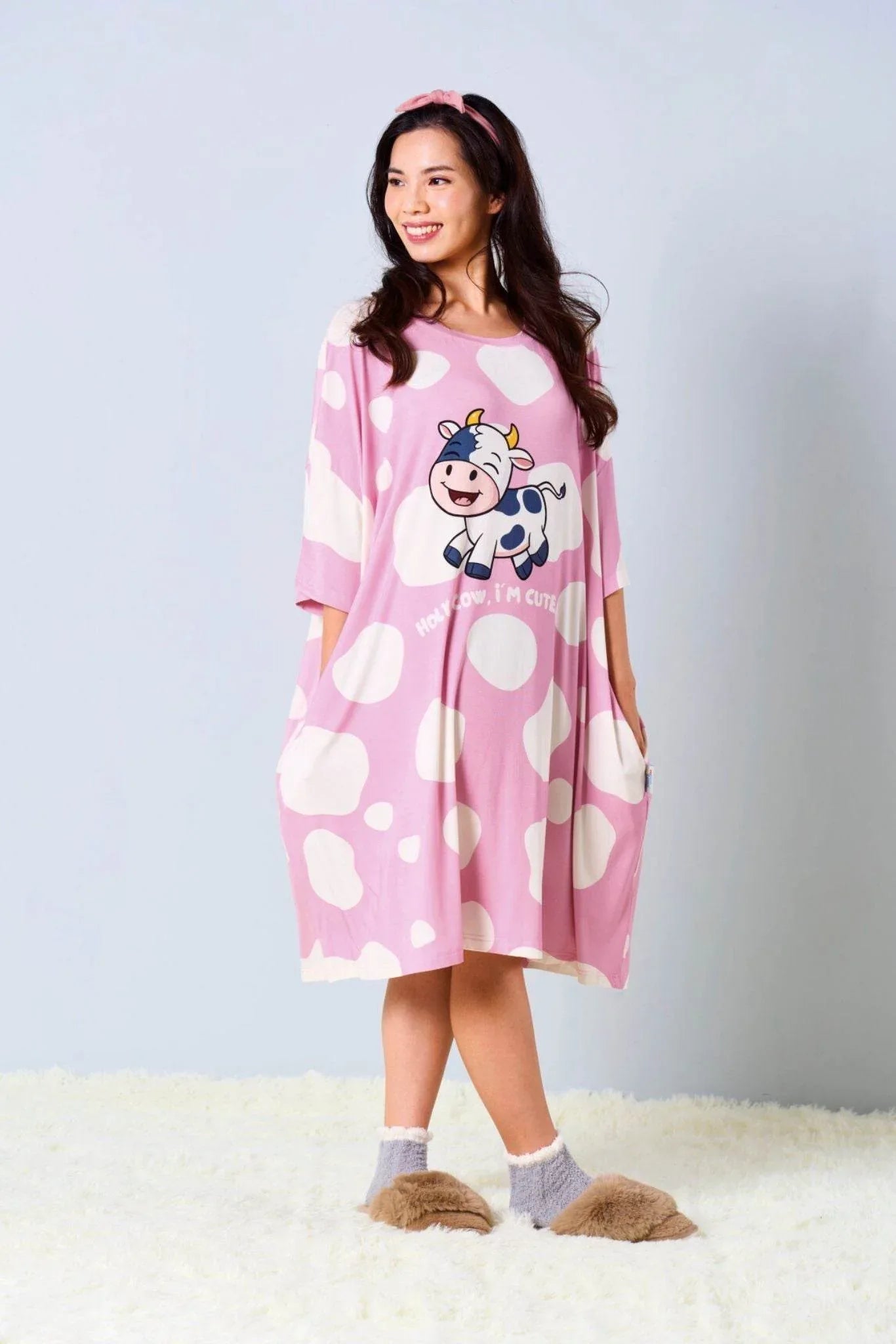 Woman wearing a pink bamboo sleep tee  by mysleeptee with a cow design on a white background