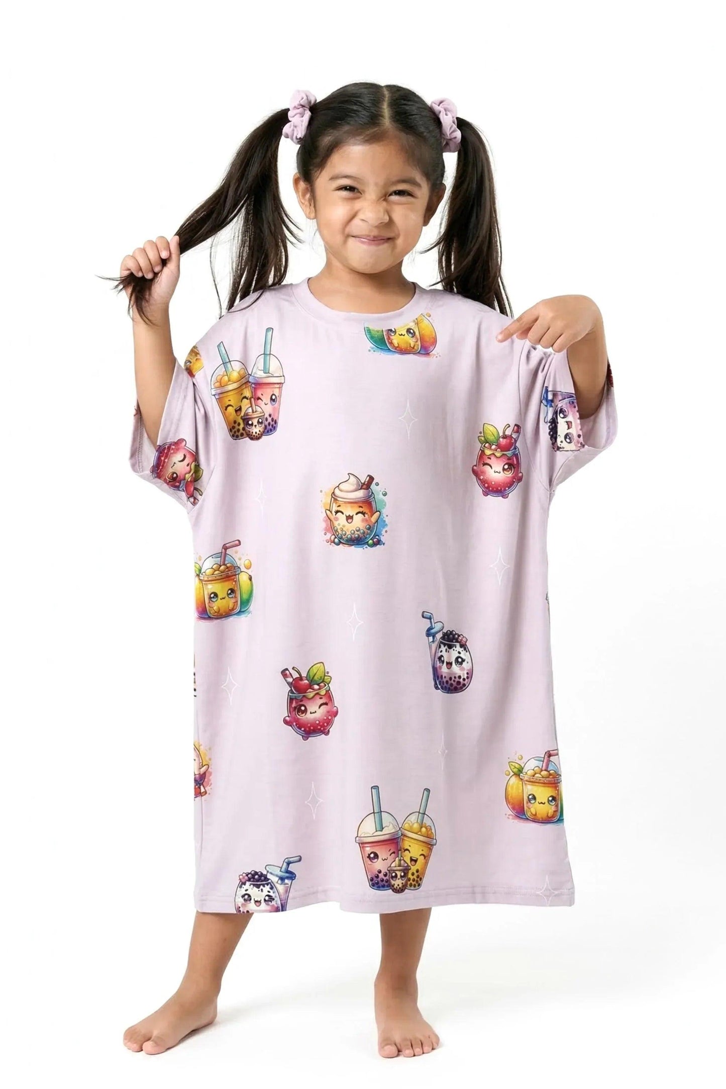 A playful little girl holding one of her pigtails with one hand while using the other hand to point excitedly at the adorable boba graphics on her MySleepTee™ The Bubble Tee | Kids bamboo sleepwear.