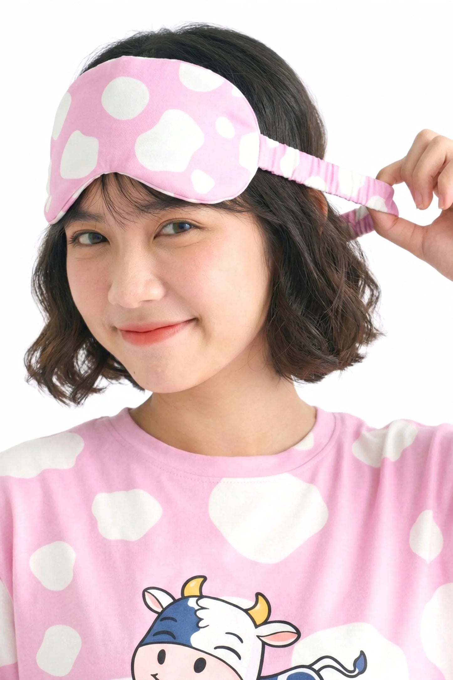 Woman showing elastic strap detail on pink cow print bamboo sleep mask