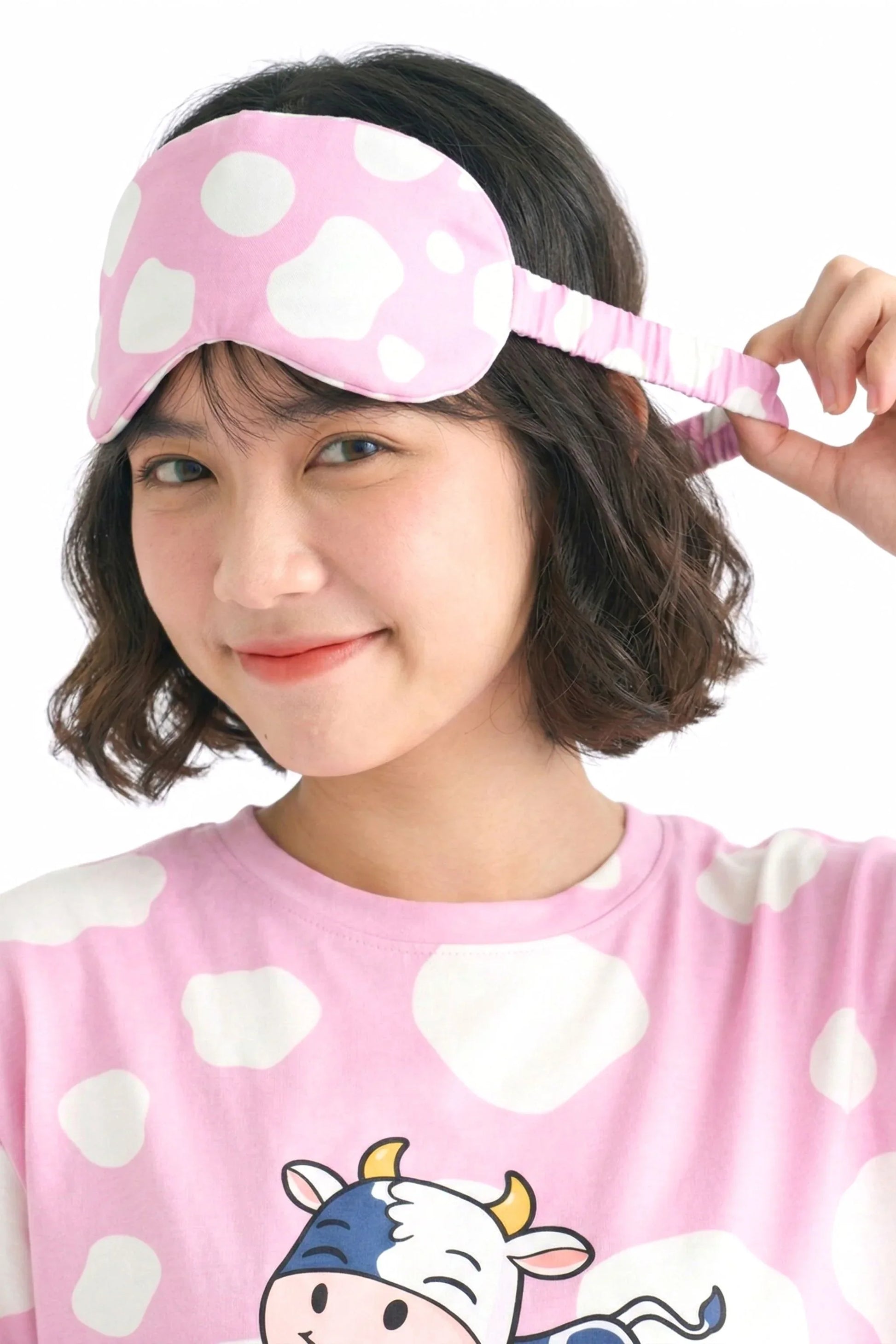 Woman showing elastic strap detail on pink cow print bamboo sleep mask