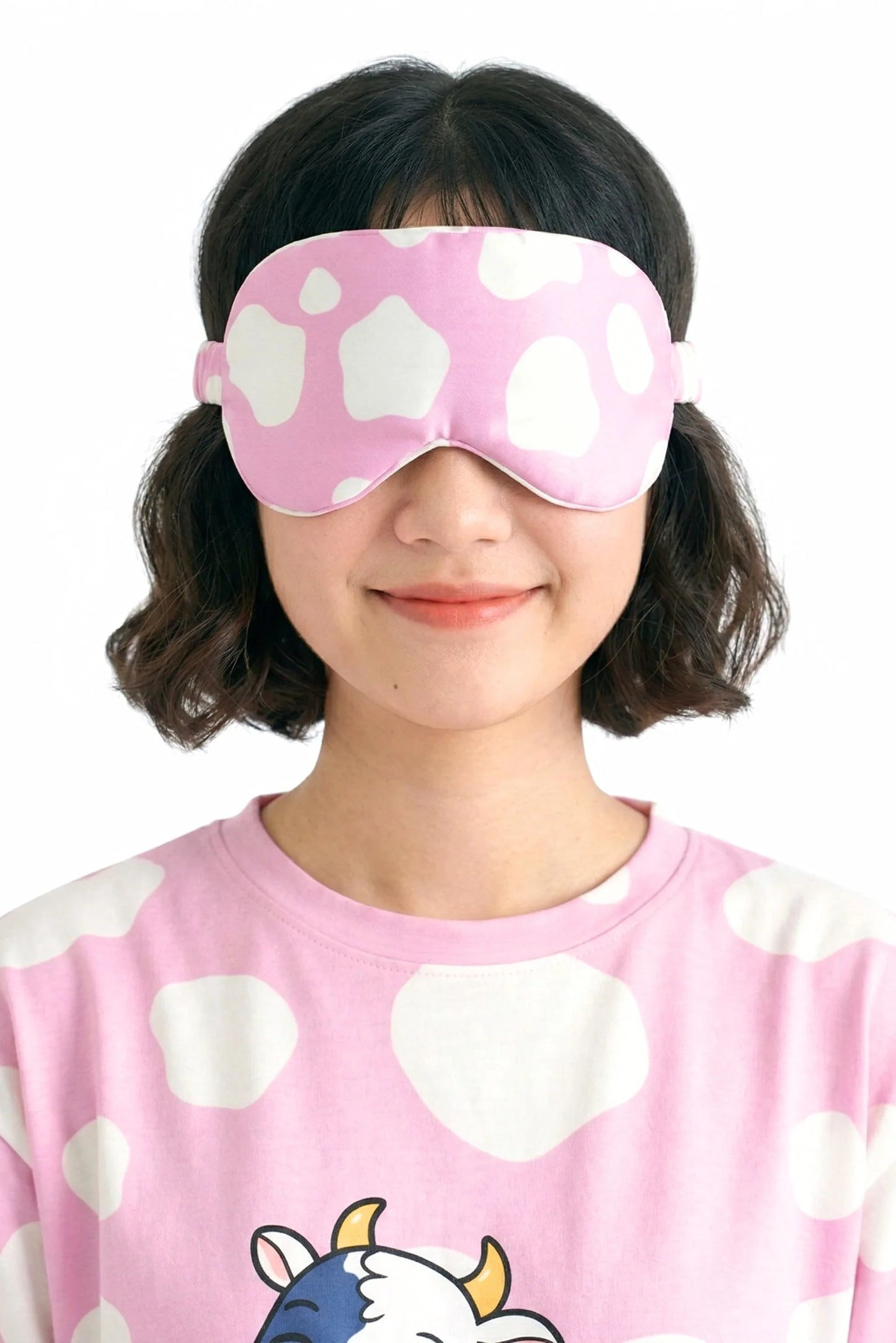 Woman wearing pink cow print bamboo sleep mask with matching Moo-nlight sleep tee