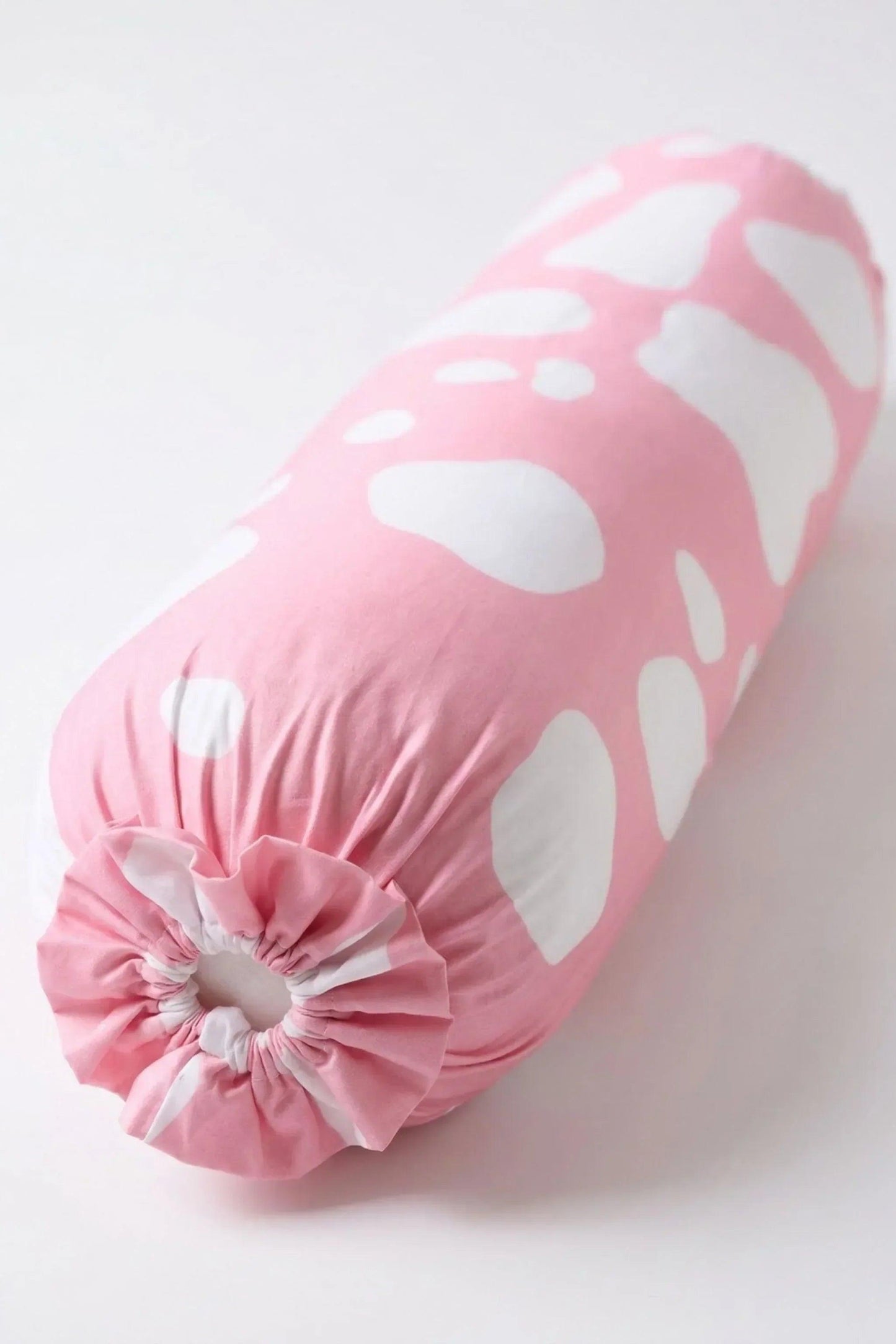An angled studio shot of the Moo-nlight bolster cover showcasing the aesthetic pink and white cow pattern.