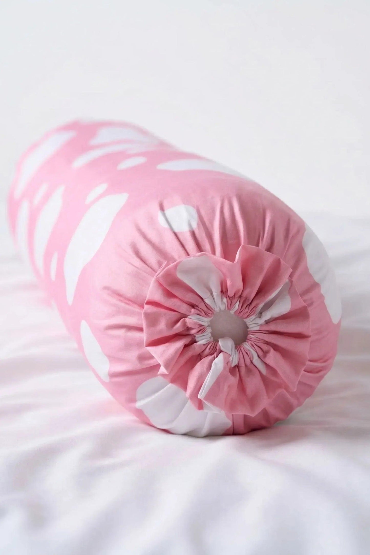 Close-up of the gathered ruffled drawstring end on the pink and white cow spot Moo-nlight bolster cover.