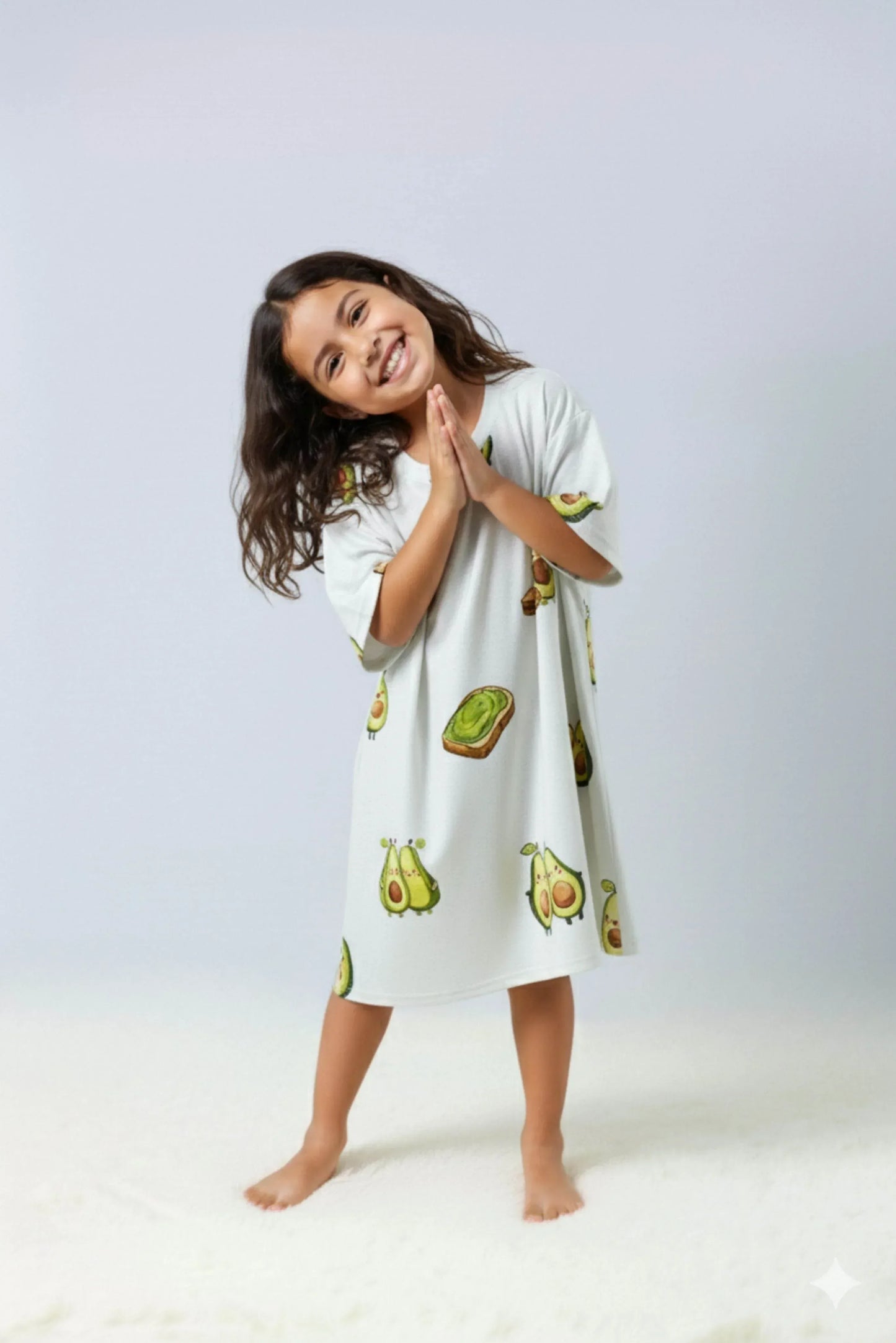 Young girl wearing avocado and toast themed oversized bamboo loungewear on a plain background