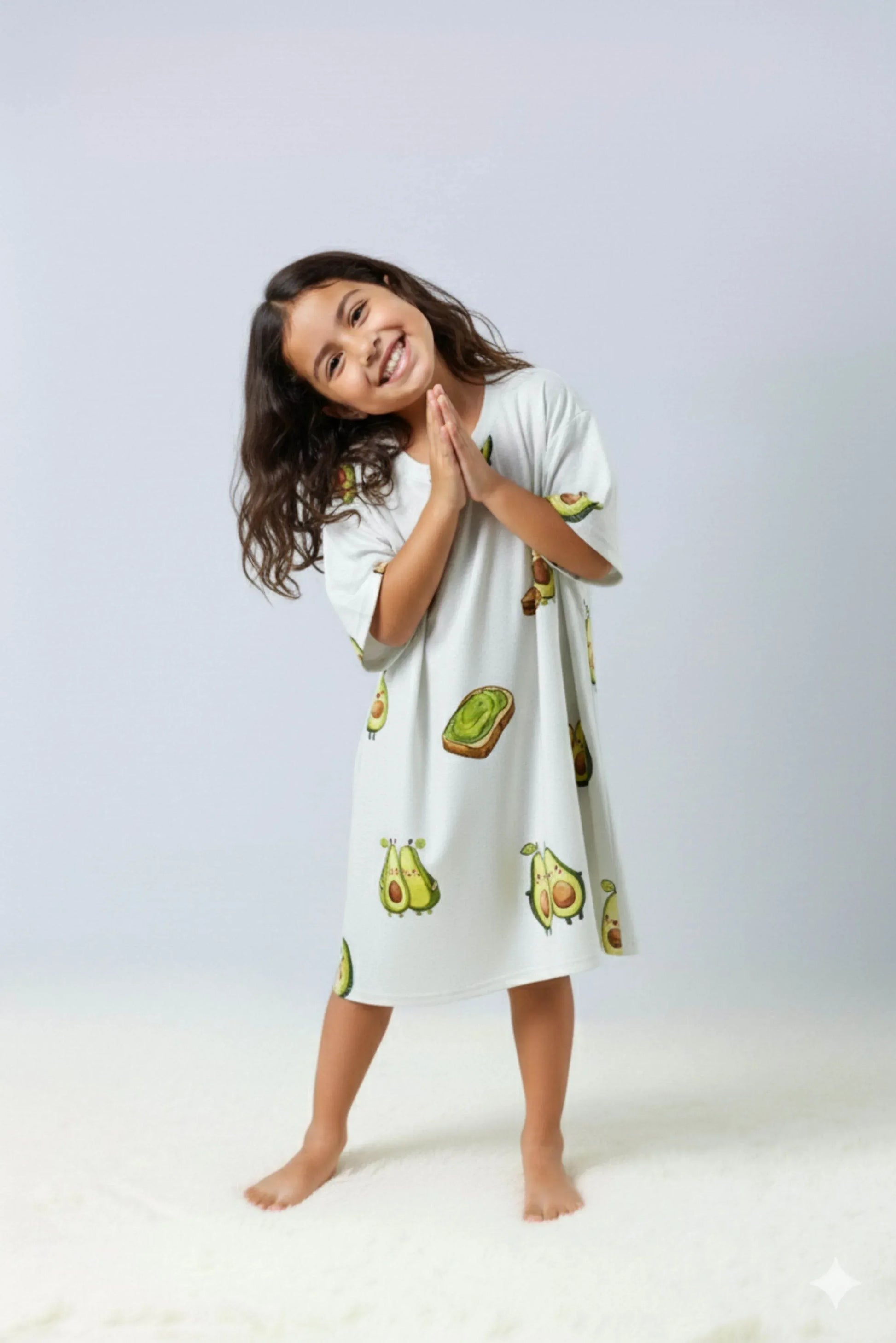 Young girl wearing avocado and toast themed oversized bamboo loungewear on a plain background