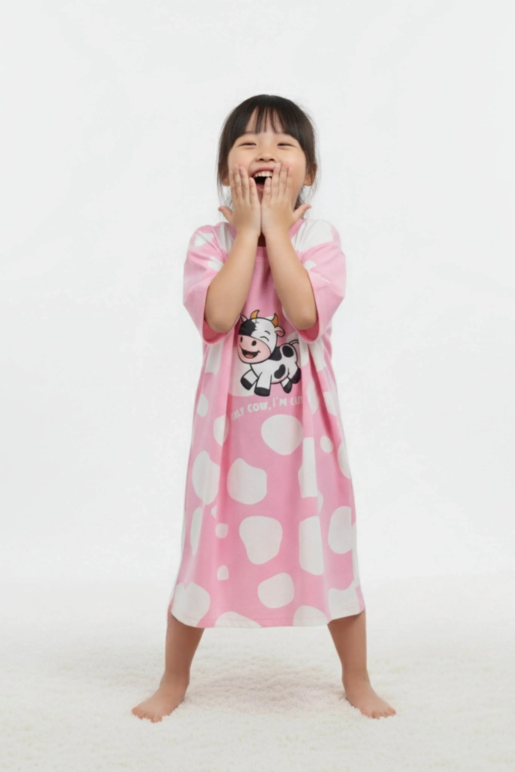 Child wearing pink cartoon-themed oversized sleepwear on a white background