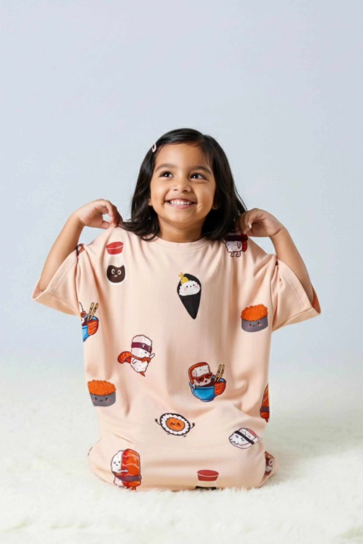 Child wearing a light pink t-shirt with cartoon food designs on a white background