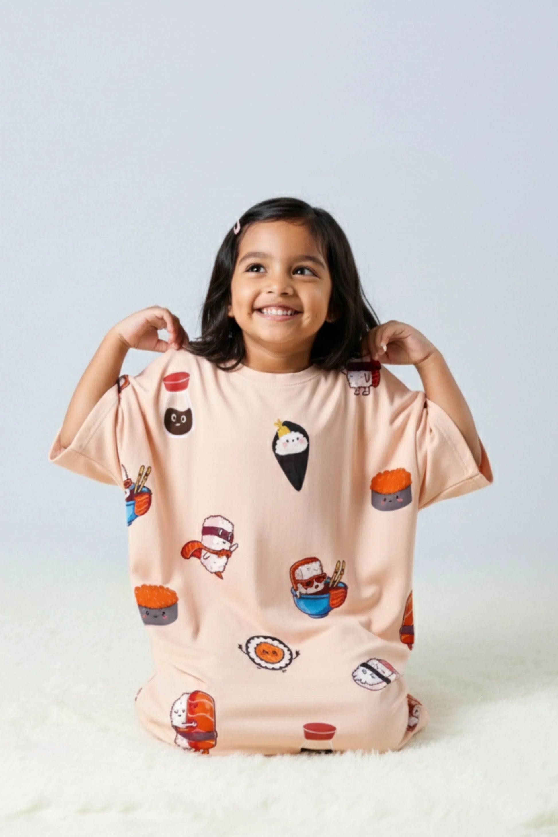 Child wearing a light pink t-shirt with cartoon food designs on a white background