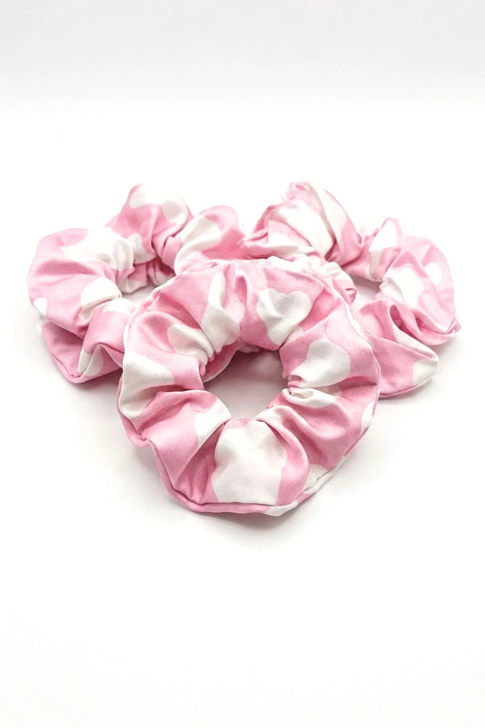 Set of three pink and white cow print bamboo scrunchies arranged in a heart shape