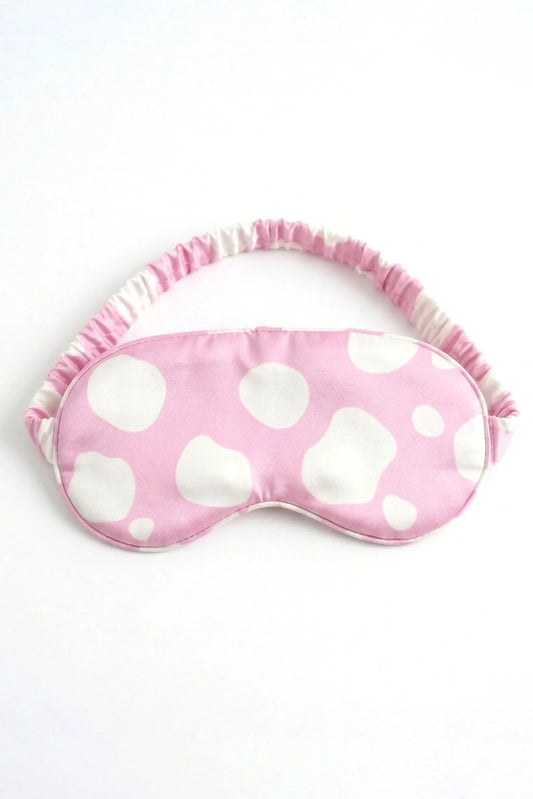 Pink and white cow print bamboo sleep mask with elastic strap on white background