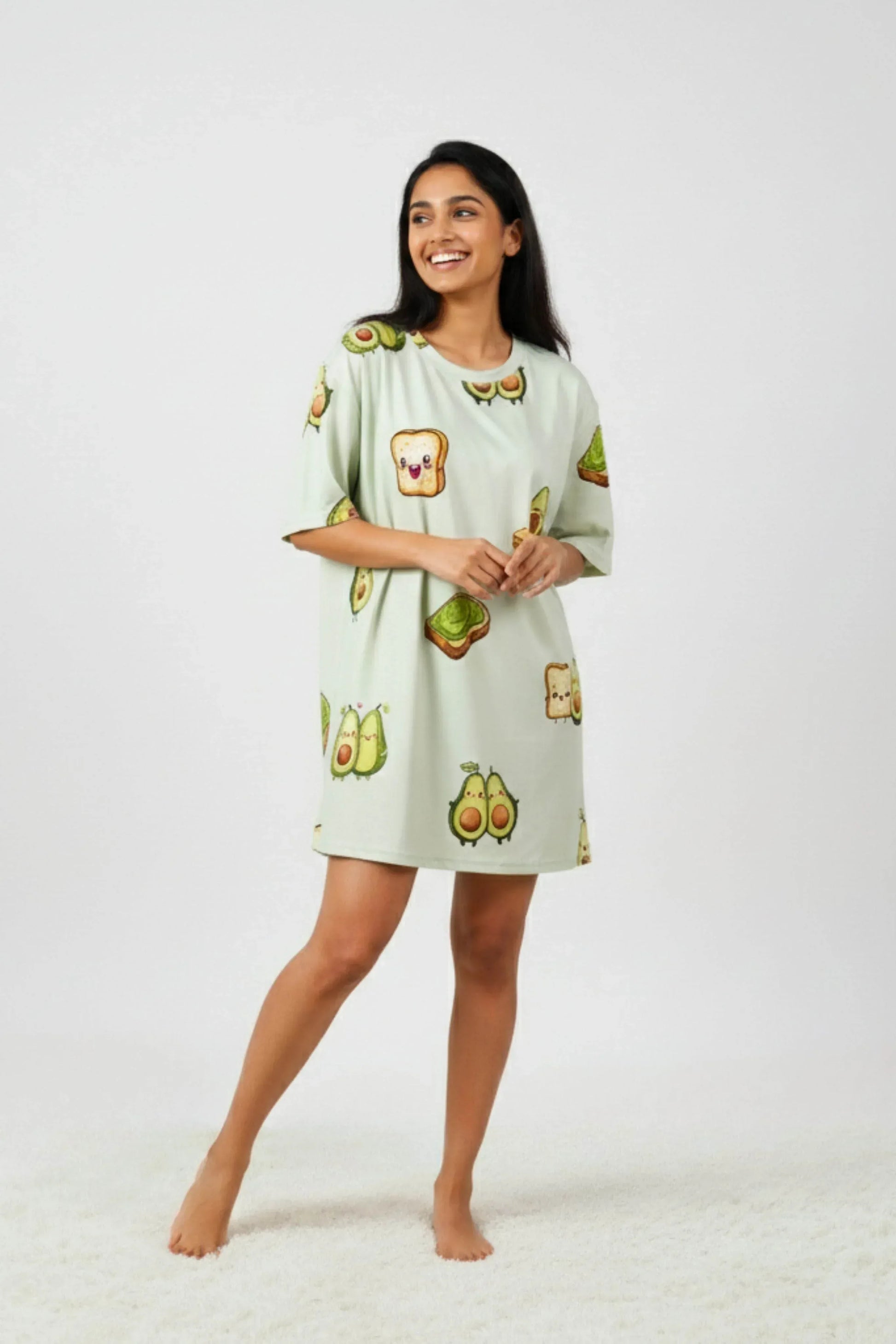 Woman wearing a light green dress with avocado print on a white background