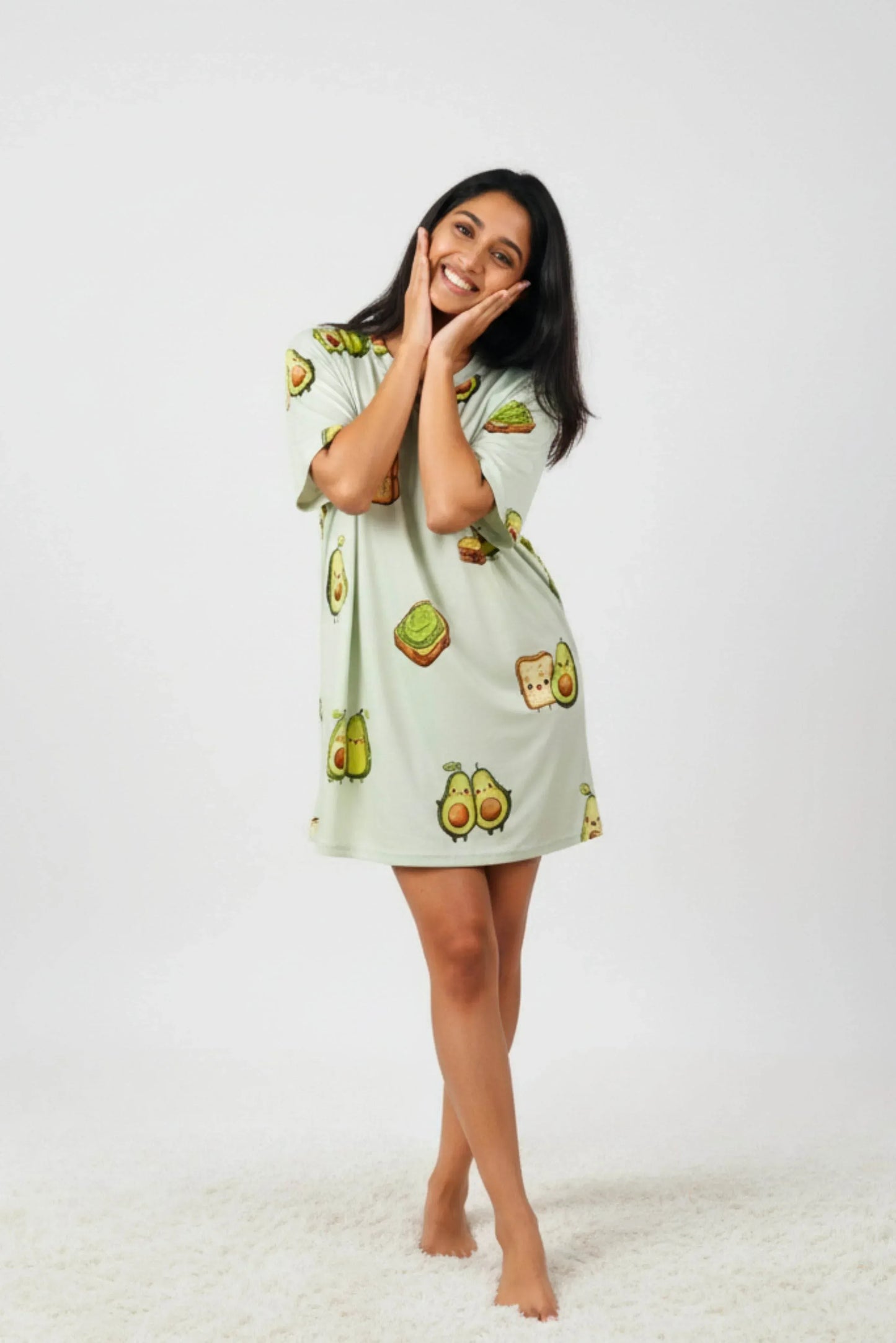 Woman wearing light green oversized bamboo loungewear with cute avocado cartoon prints on a white background