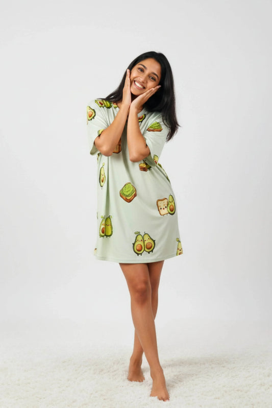 Woman wearing light green oversized bamboo loungewear with cute avocado cartoon prints on a white background