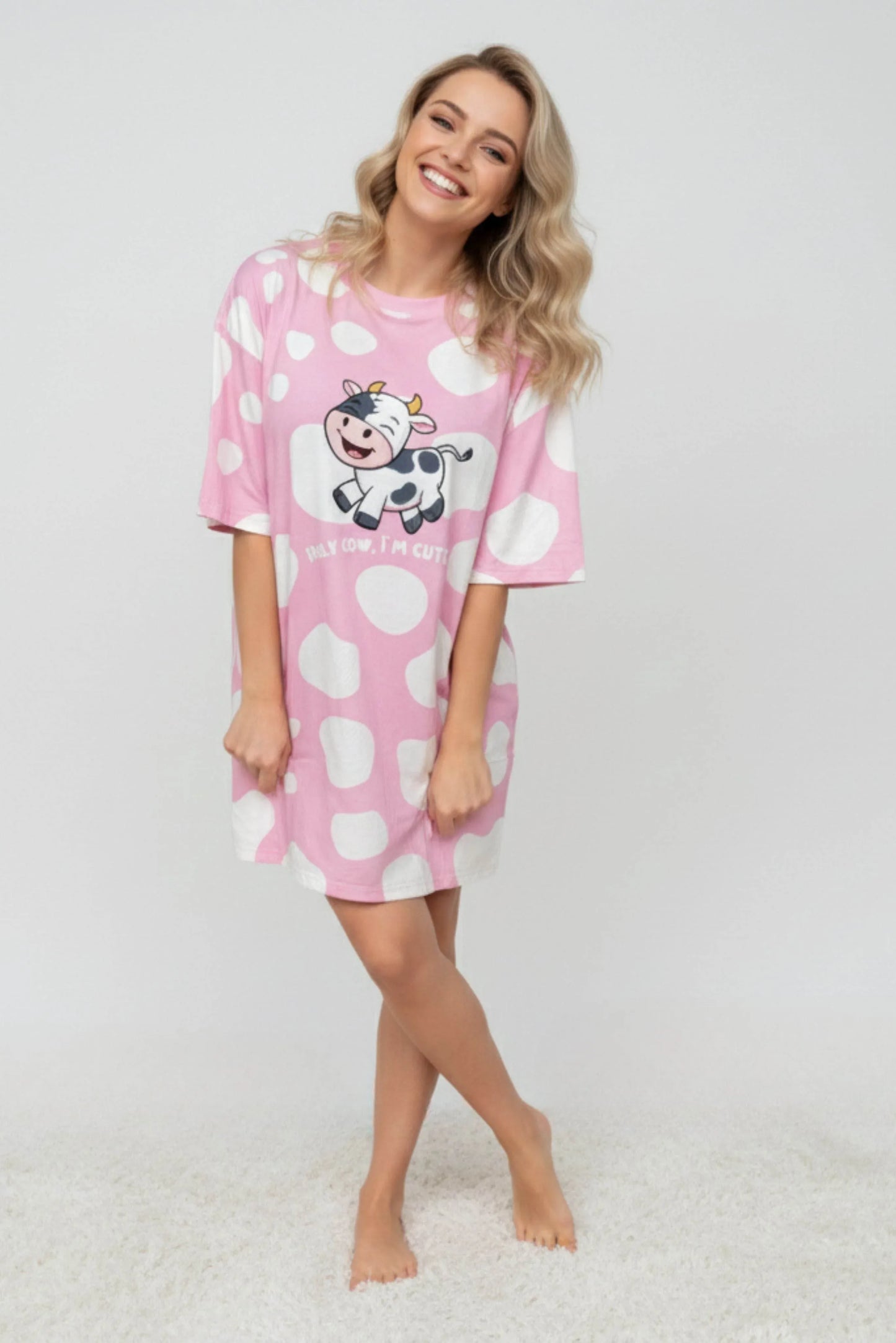 Woman wearing a pink nightshirt with a cow design on a white background