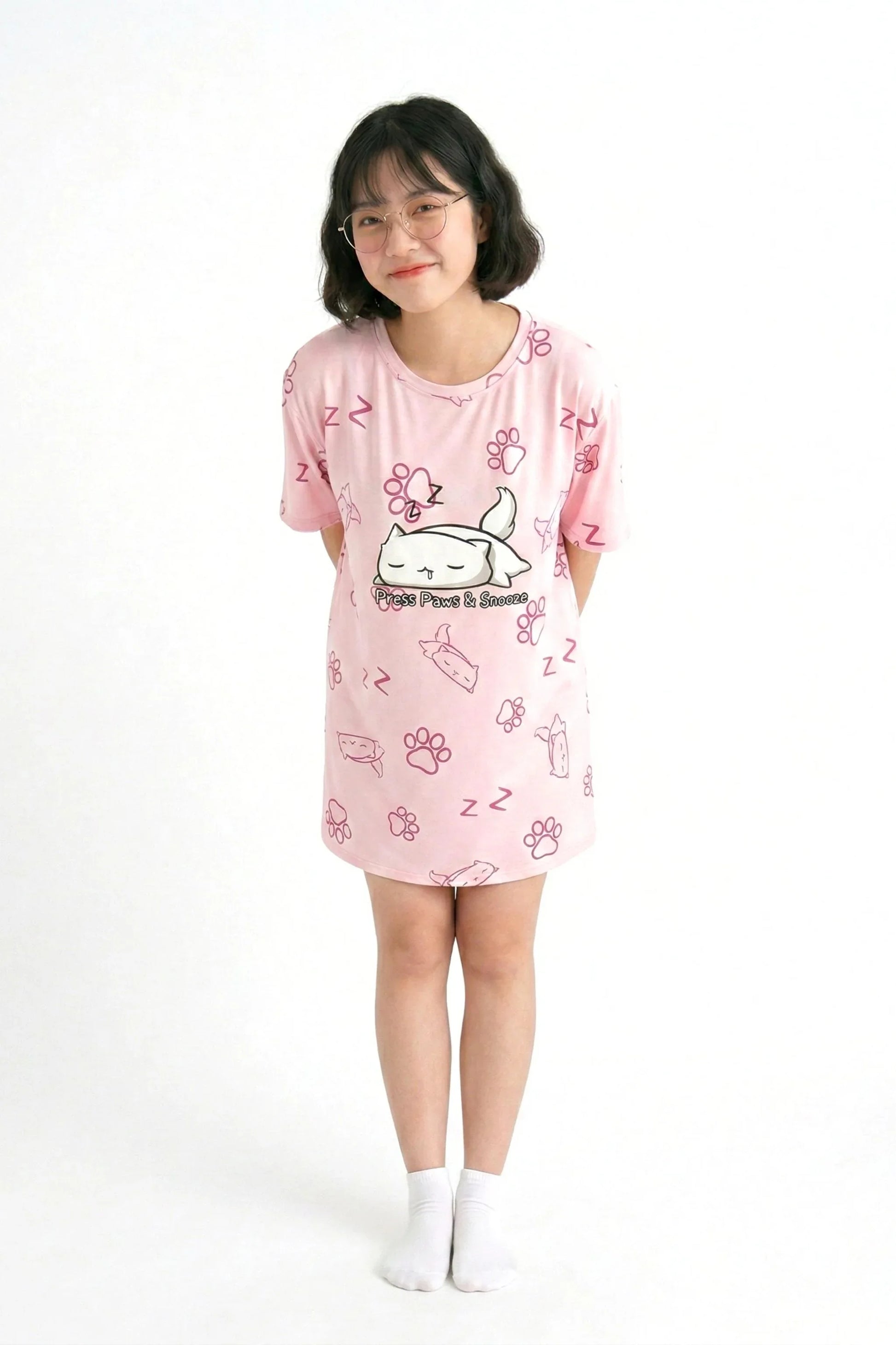A petite model wearing the "Paws & Snooze" pink bamboo nightshirt, showcasing how the oversized tee fits perfectly as a sleep dress on shorter heights.