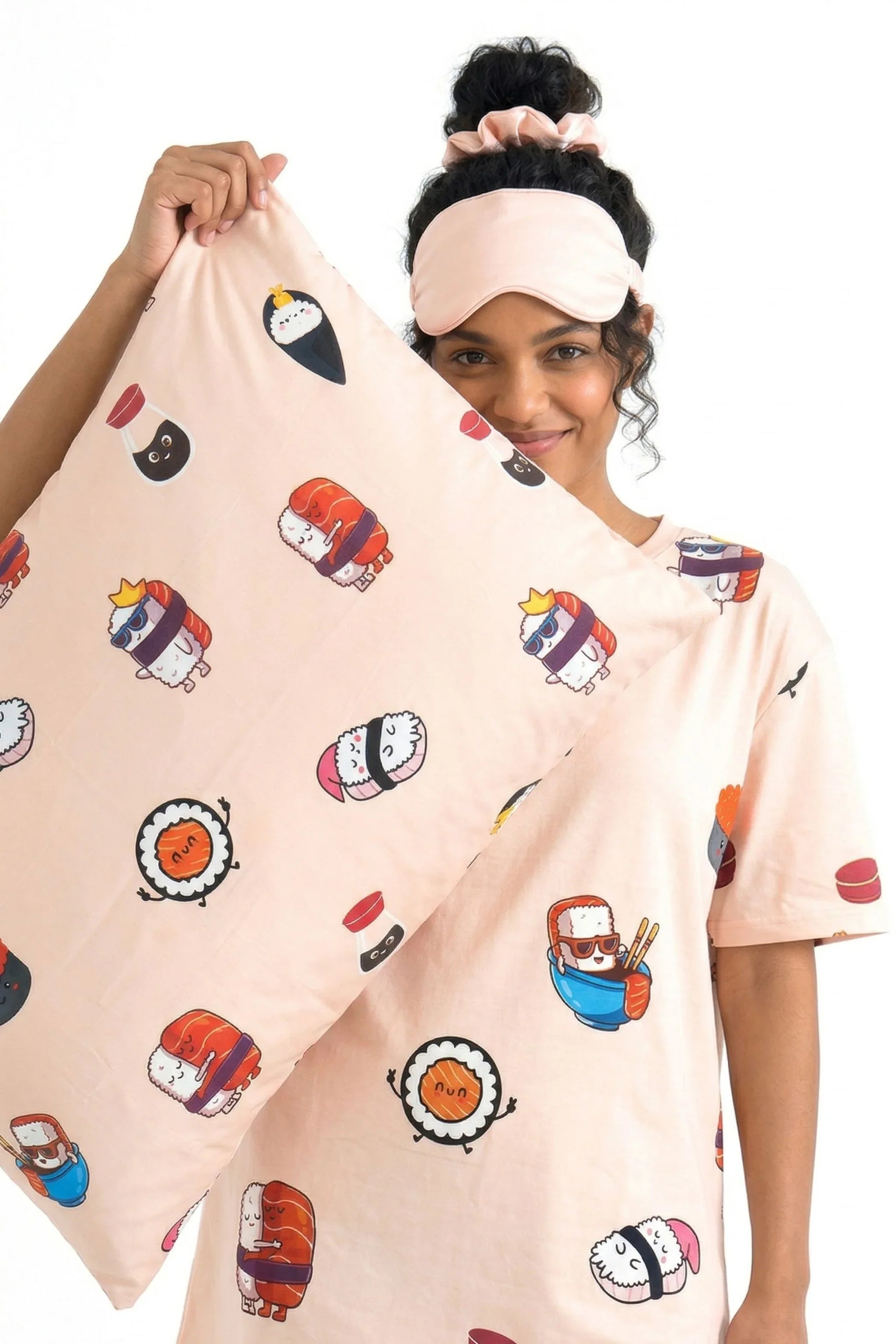 Woman holding Soy Cozy sushi print bamboo pillow case wearing matching sleep tee sleep mask and scrunchie