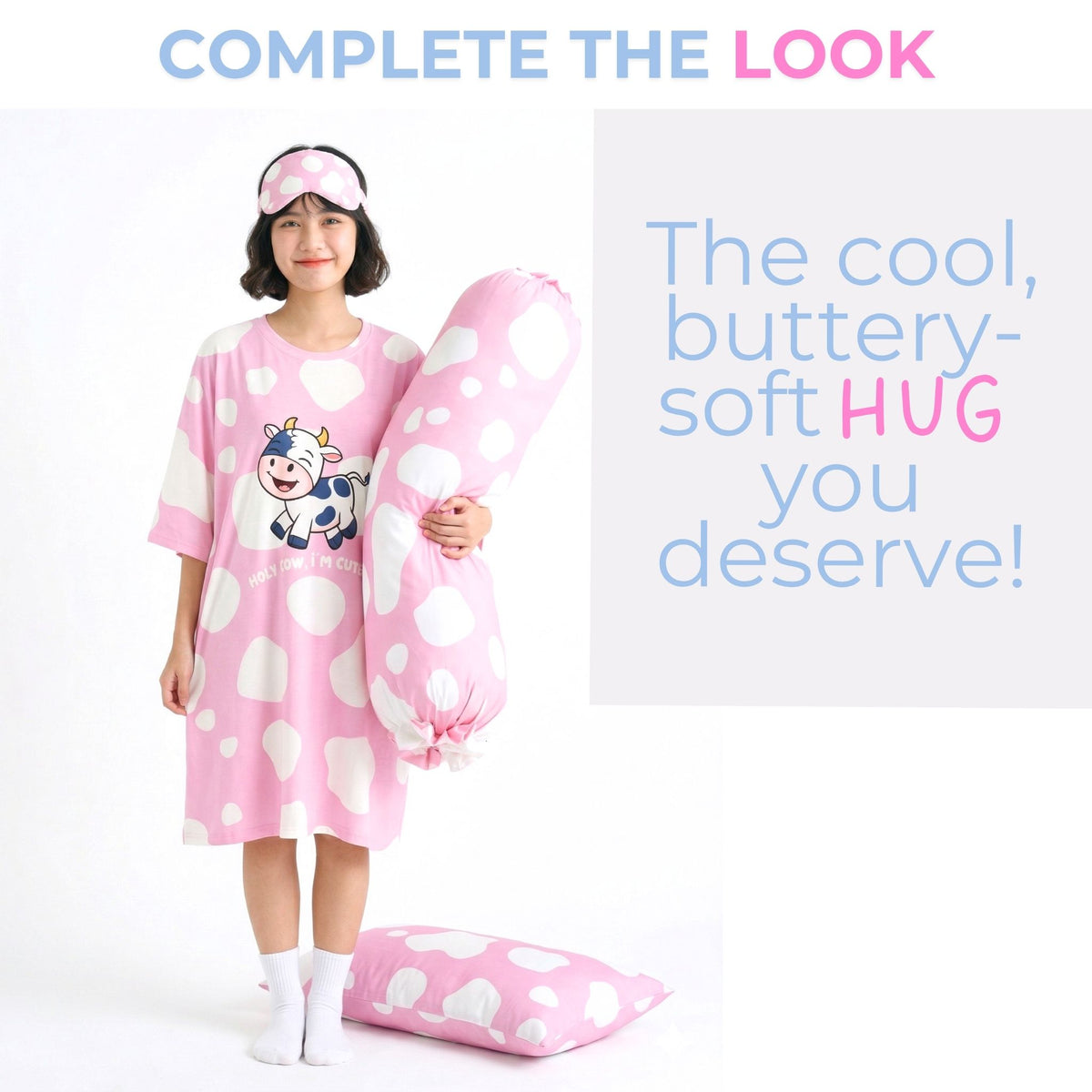A woman stands against a white studio background wearing a pink cow-print sleep tee and matching sleep mask, holding a large matching bolster. A smaller matching pillow rests on the floor, with promotional text at the top and right.