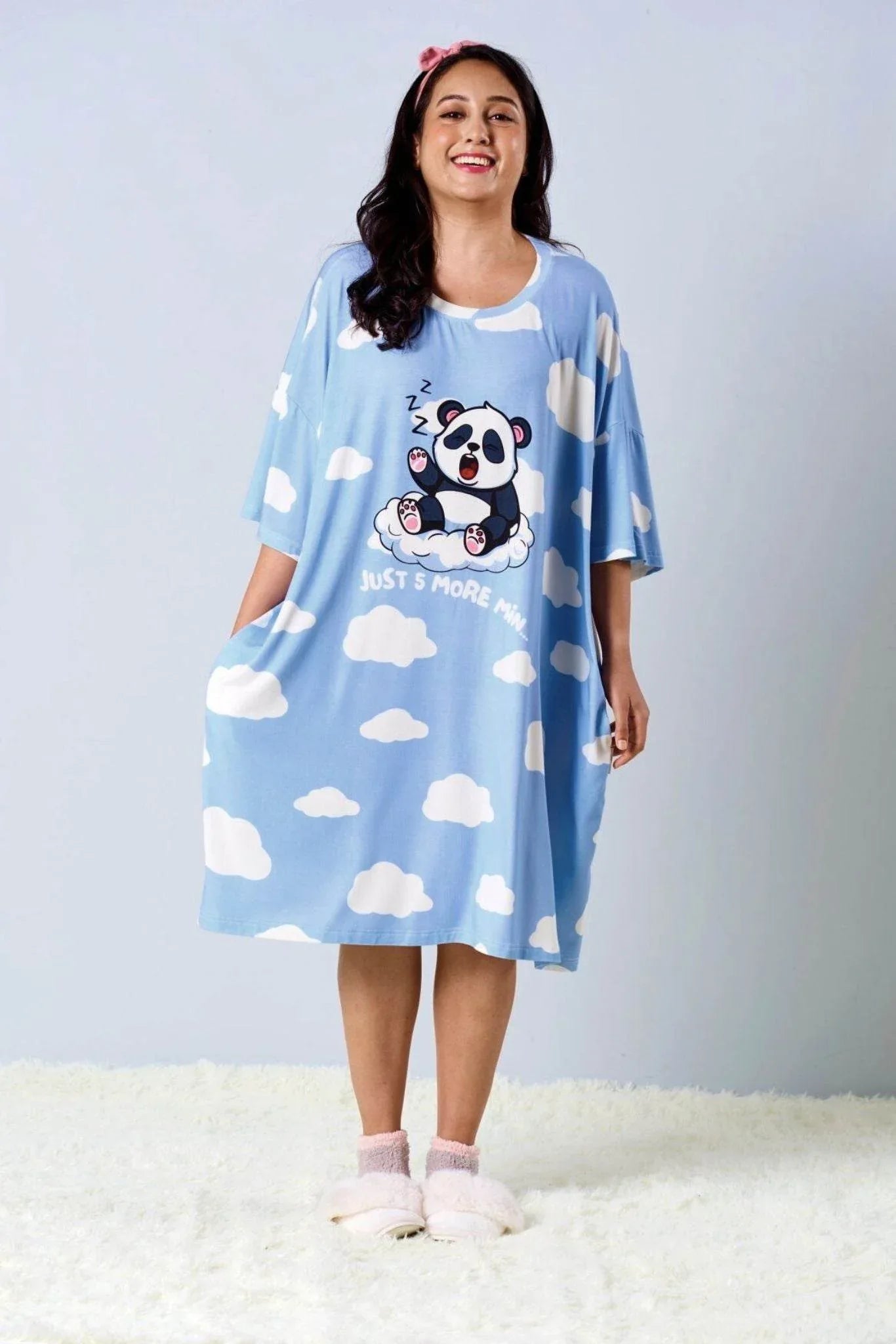Woman wearing a blue nightshirt with panda design on a light gray background