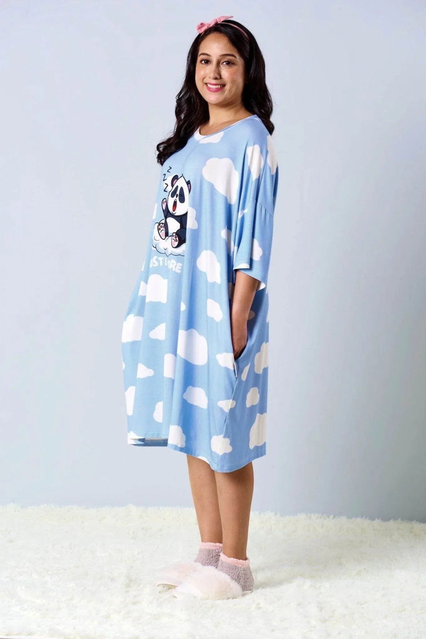 Woman wearing a light blue nightshirt from MysleepTee with cloud pattern on a white background
