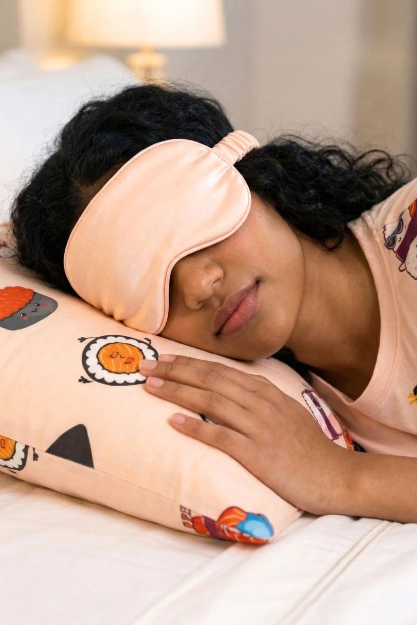 Woman sleeping on Soy Cozy sushi print bamboo pillow case wearing matching sleep mask and bamboo sleep tee