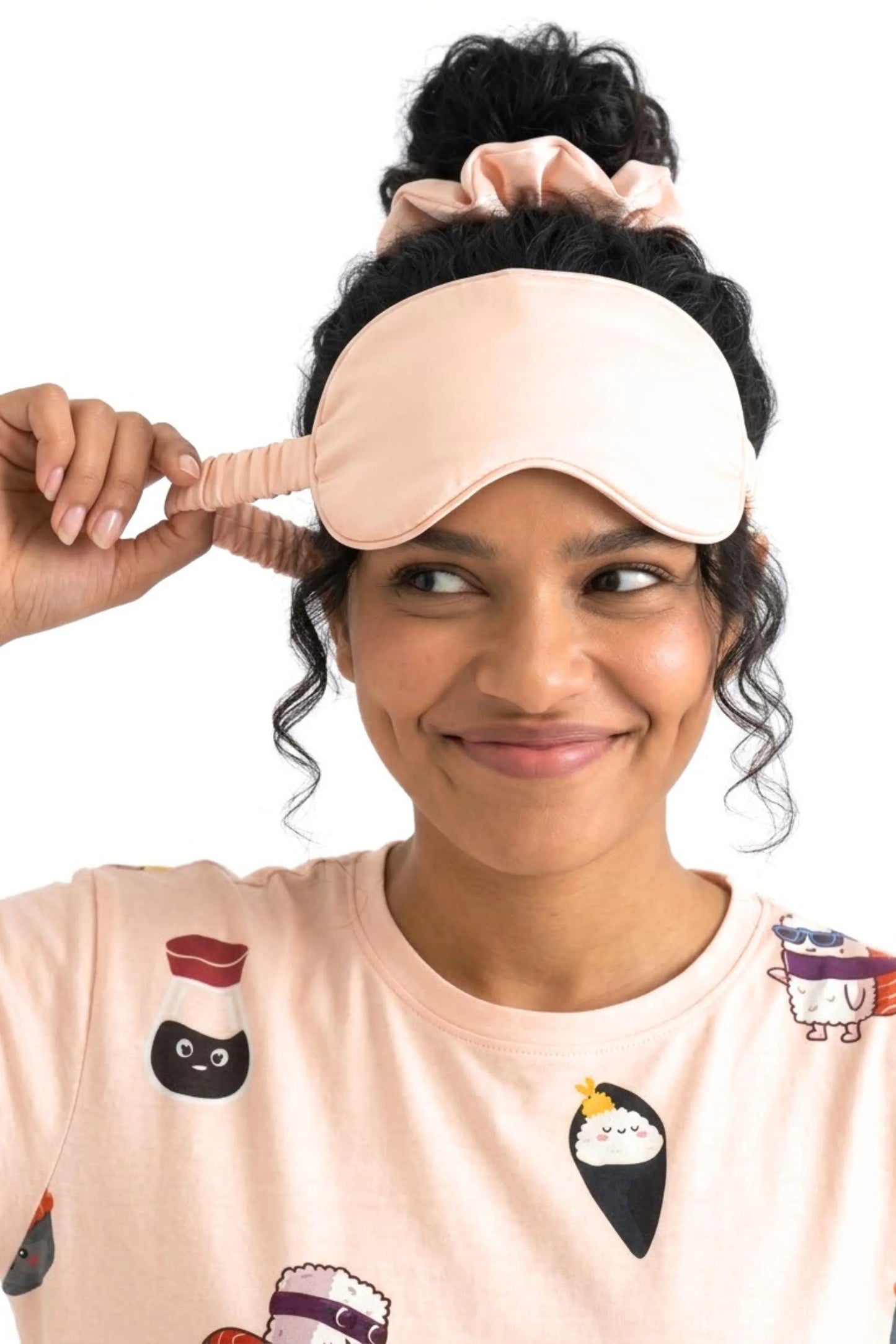 Woman showing elastic strap on salmon pink bamboo sleep mask wearing matching Soy Cozy sushi print sleep tee