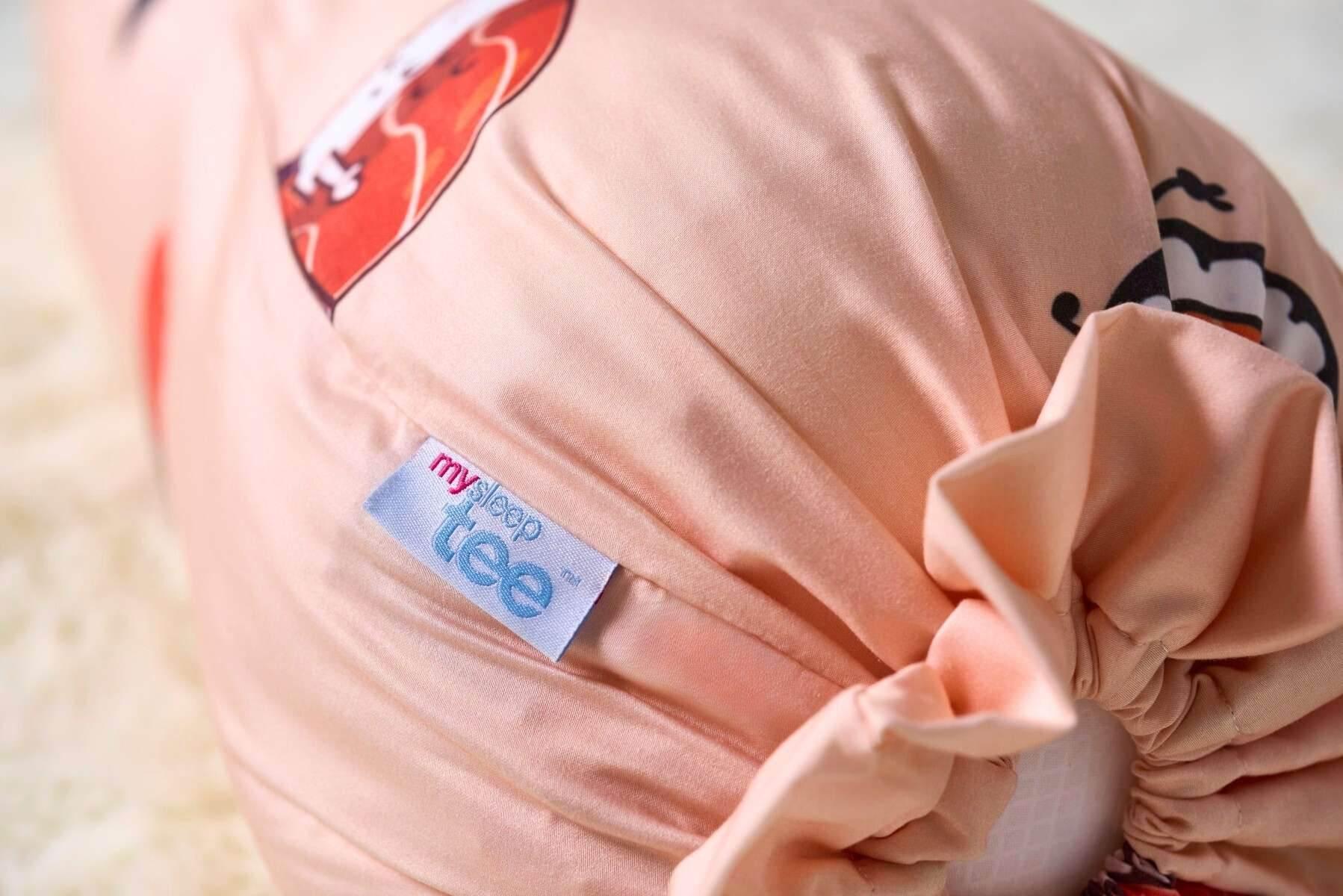 Close-up of a peach-colored bolster with a 'mysleeptee' label on a soft surface.