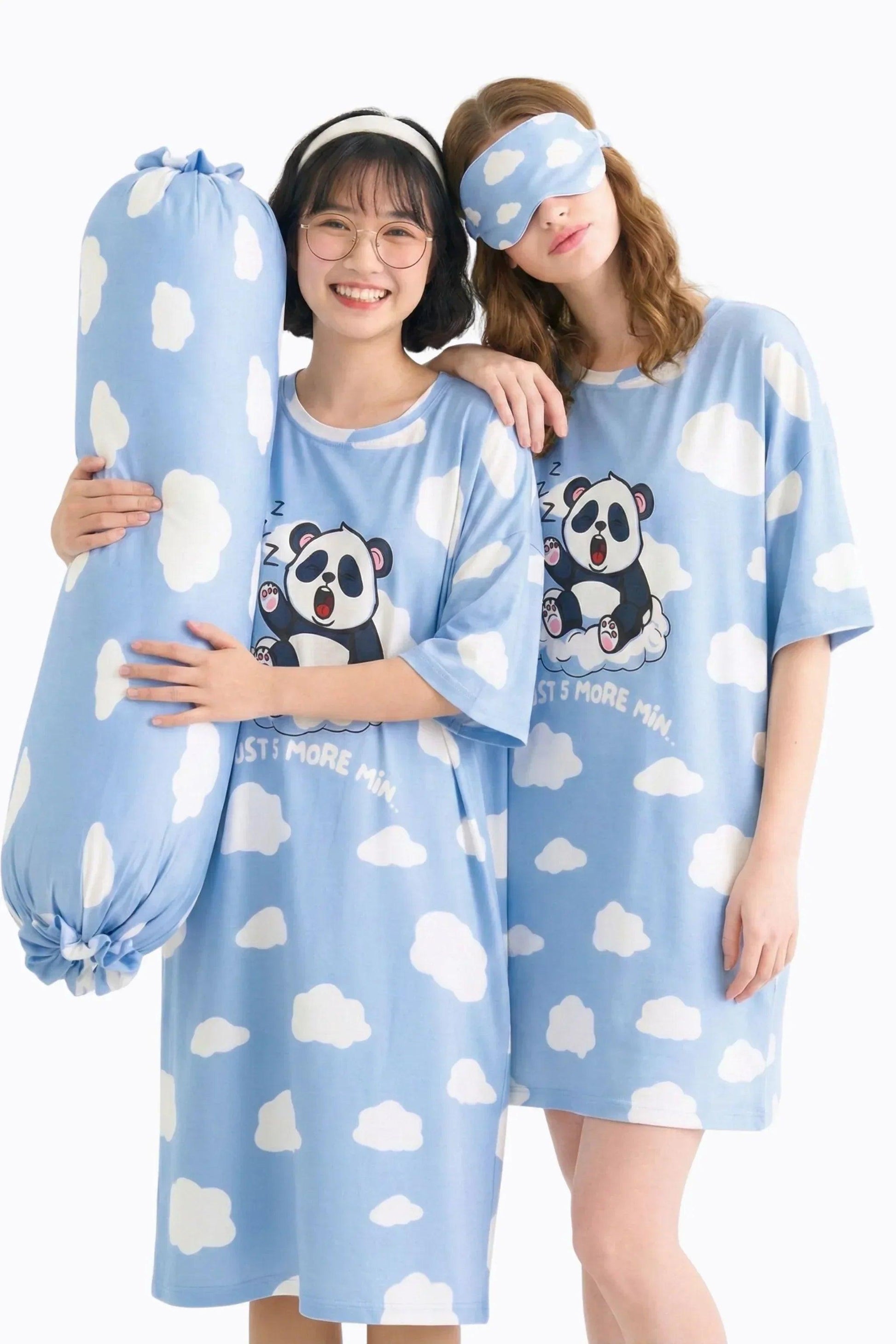 Two models in a studio setting showcasing the Un-bear-ably Sleepy collection by MySleepTee. One model holds the light blue, cloud-patterned bamboo bolster cover while wearing a matching panda oversized sleep tee. The second model wears a coordinating cloud sleep mask and panda shirt, demonstrating the complete cozy sleep set.