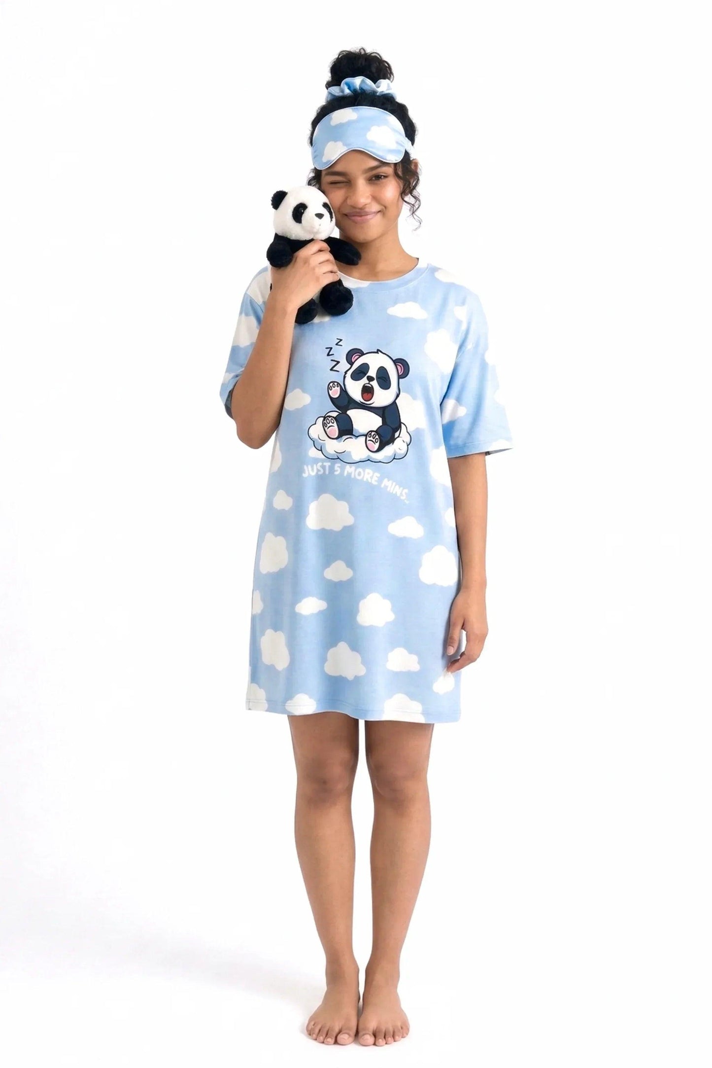 Full-body shot of a woman winking and holding a small plush panda toy to her cheek, wearing the Un-bear-ably Sleepy Petite sleep tee, matching eye mask, and scrunchie by MySleepTee.
