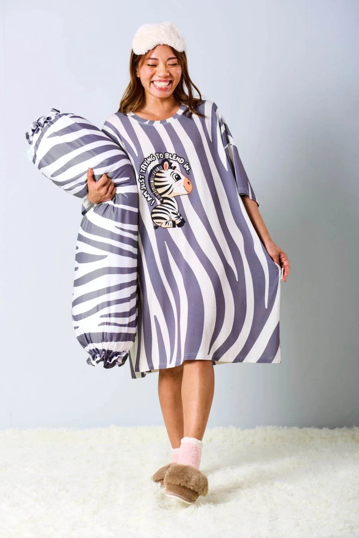 Woman wearing a zebra-striped oversized sleep tee by MySleepTee with a matching bolster cover 