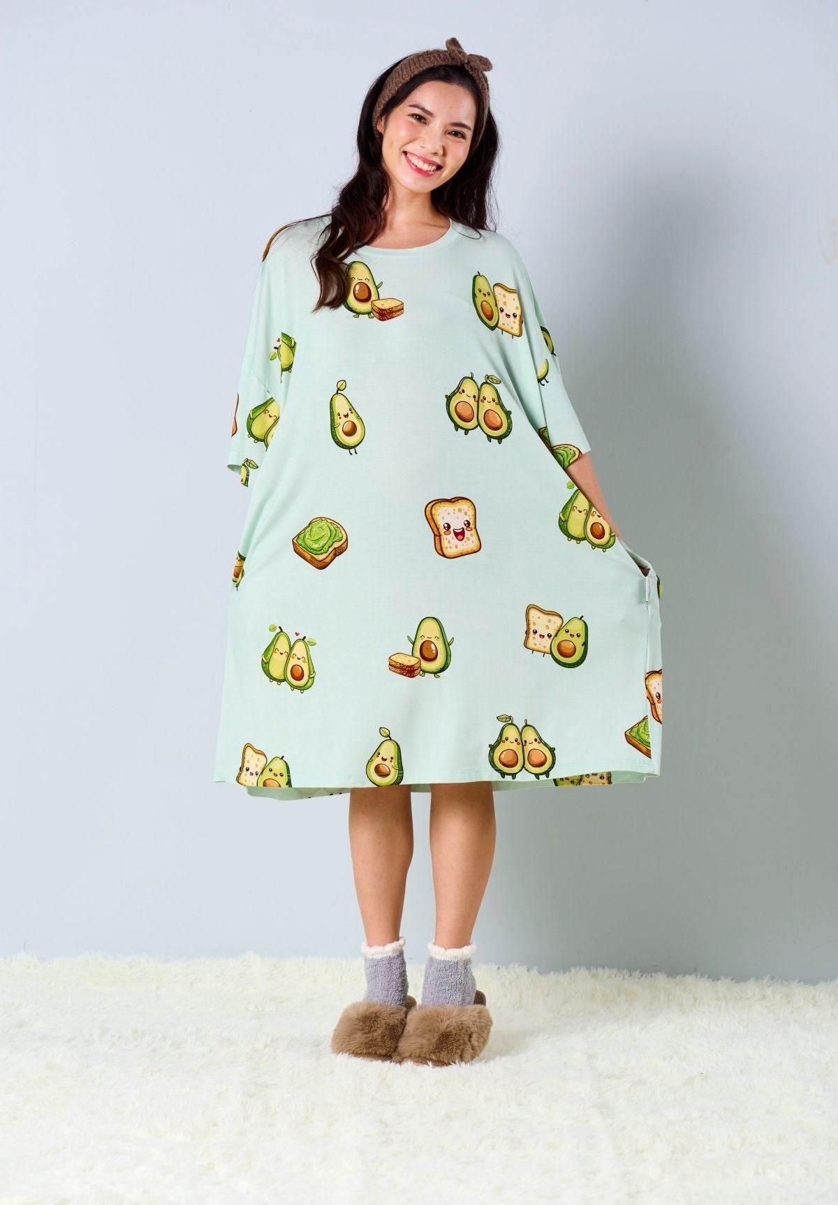 Woman wearing a light green sleep tee with avocado print against a plain background