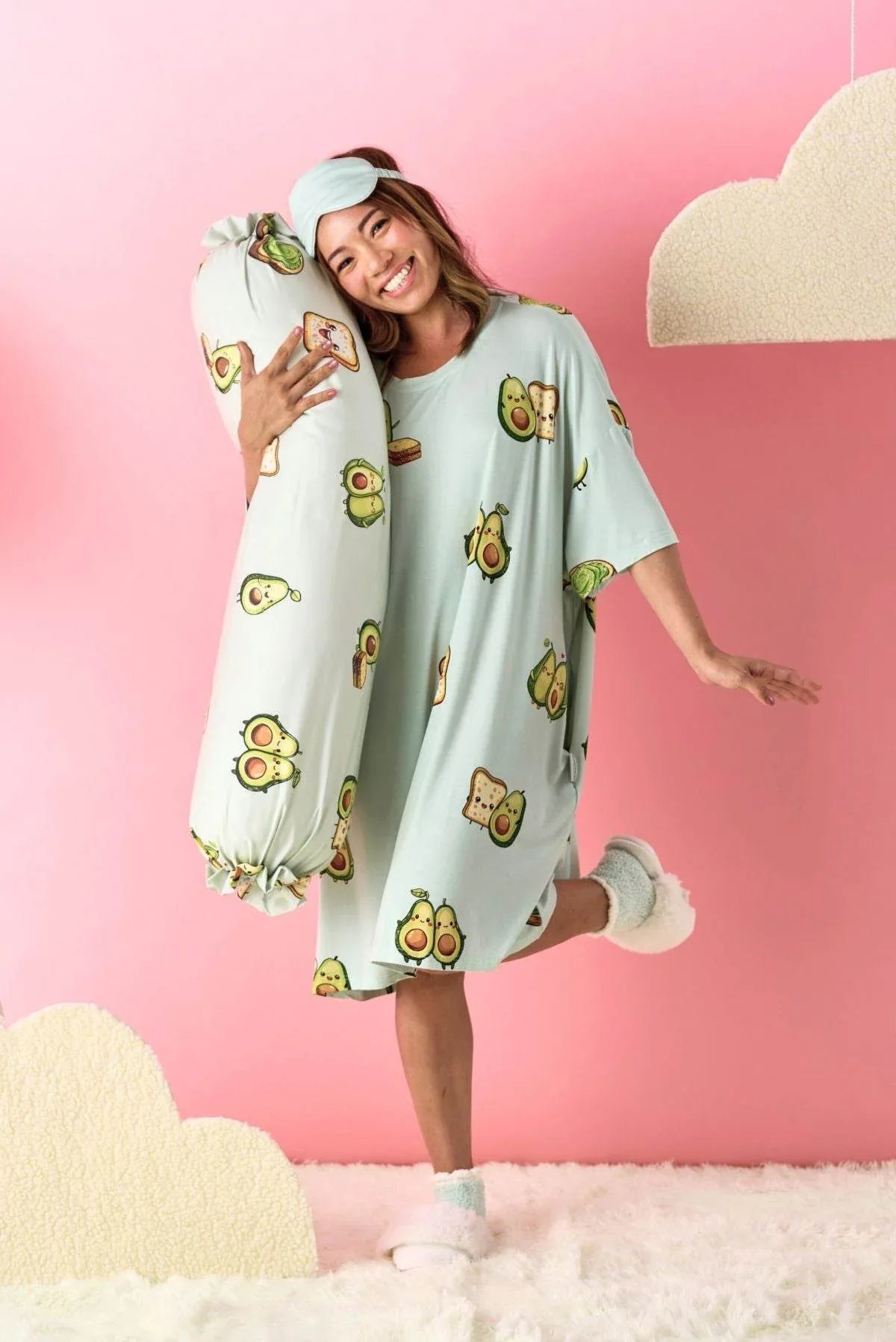 Woman wearing a light blue nightgown with avocado pattern on a pink background