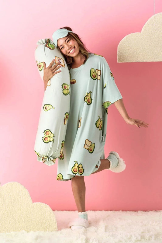 Woman wearing a light blue nightgown with avocado pattern on a pink background
