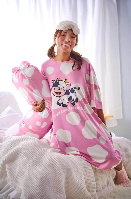 Girl wearing a pink sleep tee with a cow design, holding a matching pink pillow.
