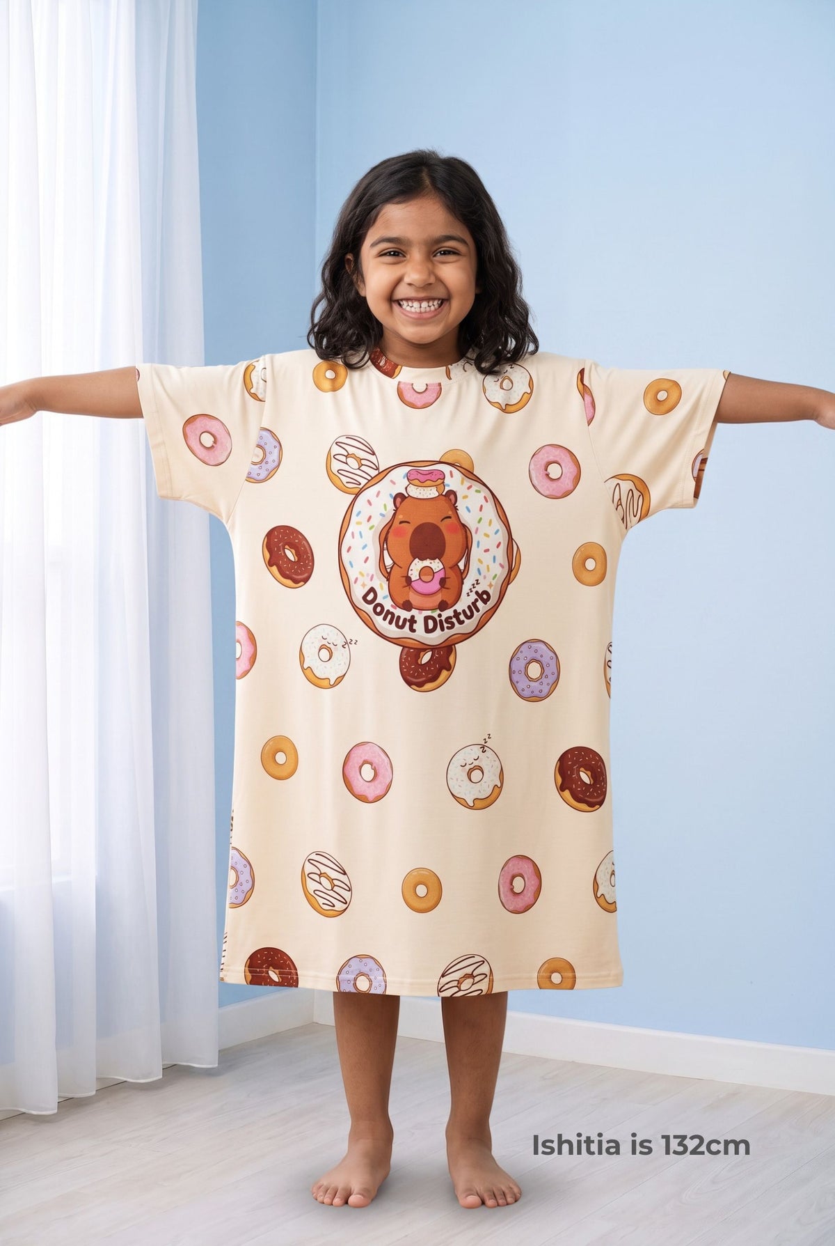 Young girl with arms outstretched in the Donut Disturb Kids sleep tee, showing the wide dropped-shoulder sleeves and roomy oversized cut.