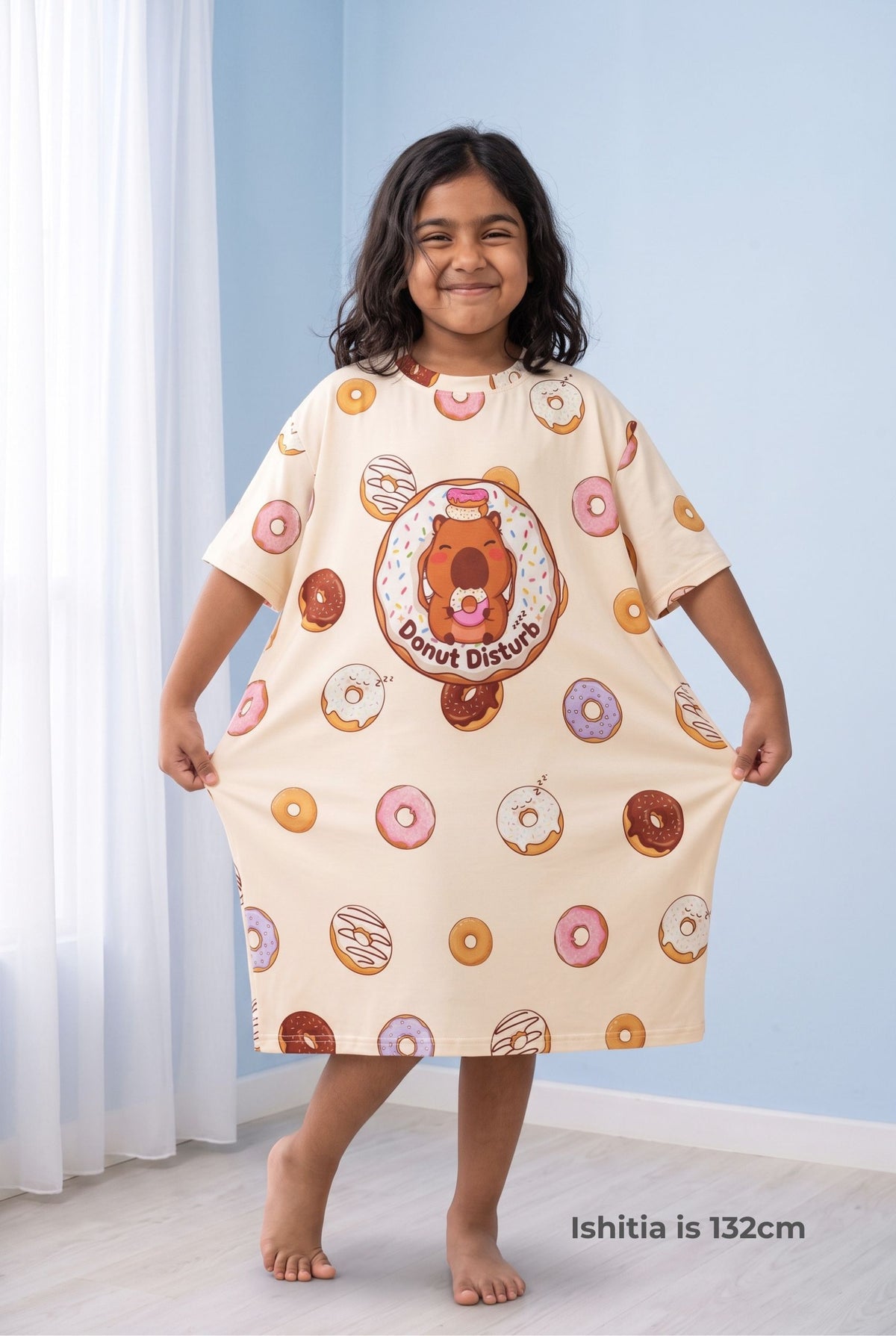 Young girl holding out the hem of the Donut Disturb Kids sleep tee to show how wide and oversized the bamboo nightdress is.