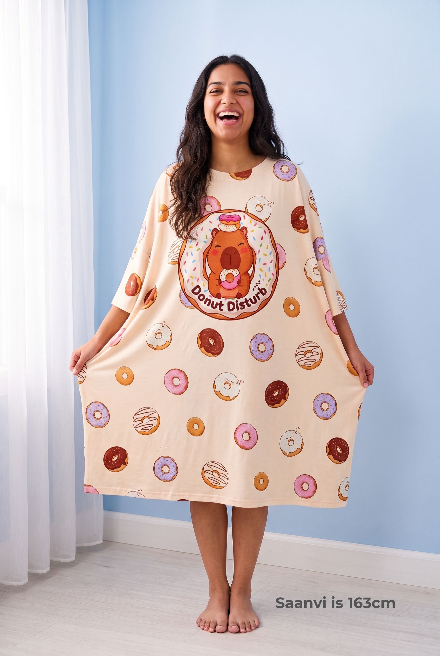 Woman holding out the hem of the ultra-oversized Donut Disturb Original sleep tee to show its full width, hem falling below the knee.