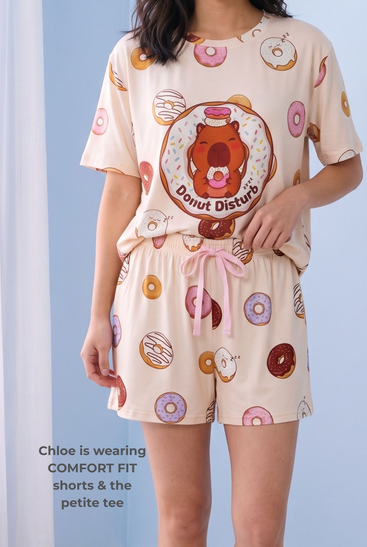 Woman wearing the Donut Disturb Comfort Fit bamboo shorts with the matching Petite sleep tee, showing the pink drawstring bow, elasticated waistband and relaxed mid-thigh fit.