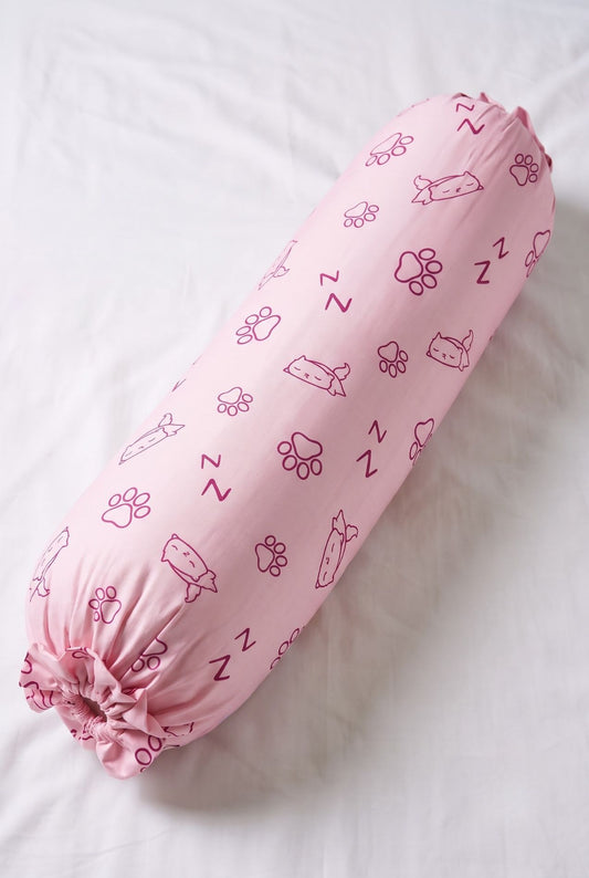 Paws & Snooze bamboo bolster cover in pink cat and paw print, flat lay on white bedding
