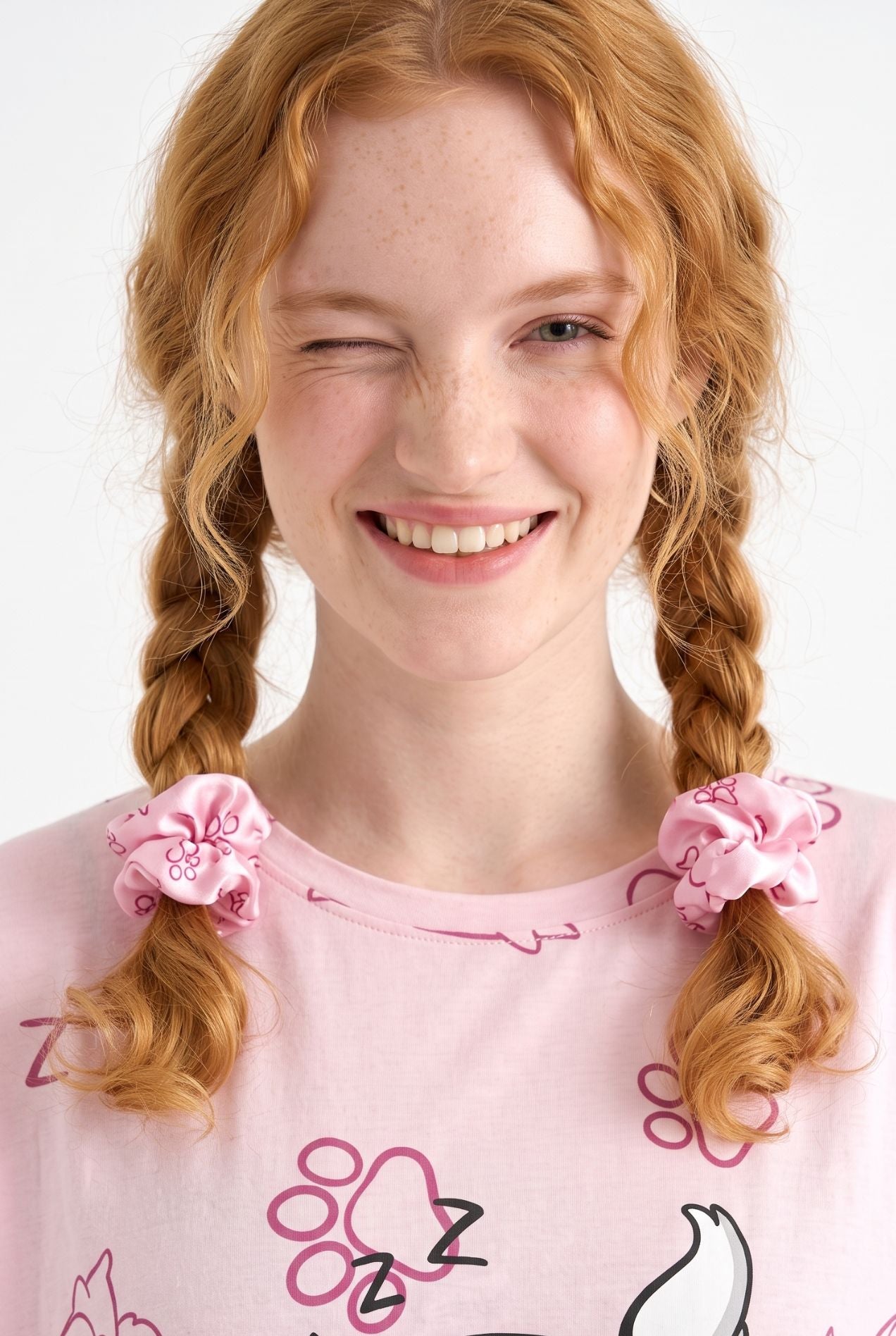 Woman wearing Paws & Snooze bamboo scrunchies in pink cat print tied in pigtails
