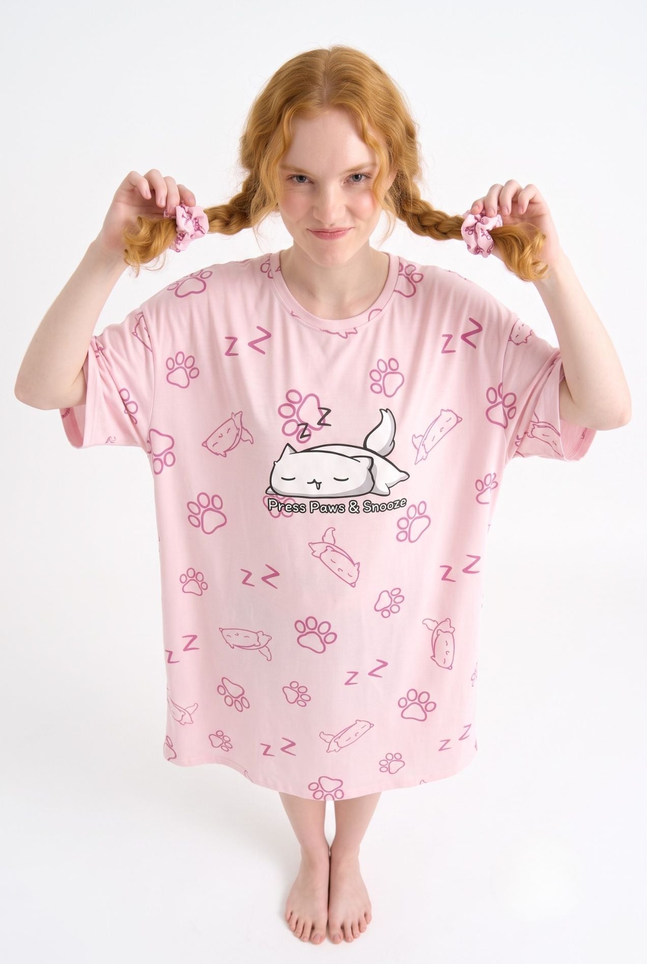 Woman wearing Paws & Snooze oversized pink cat-print sleep tee with matching scrunchies