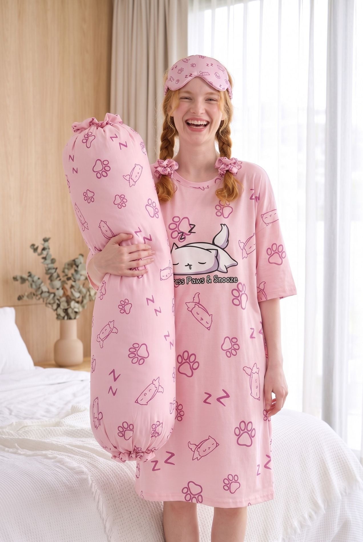 Woman wearing Paws & Snooze pink cat-print sleep tee with matching bamboo sleep mask pushed up
