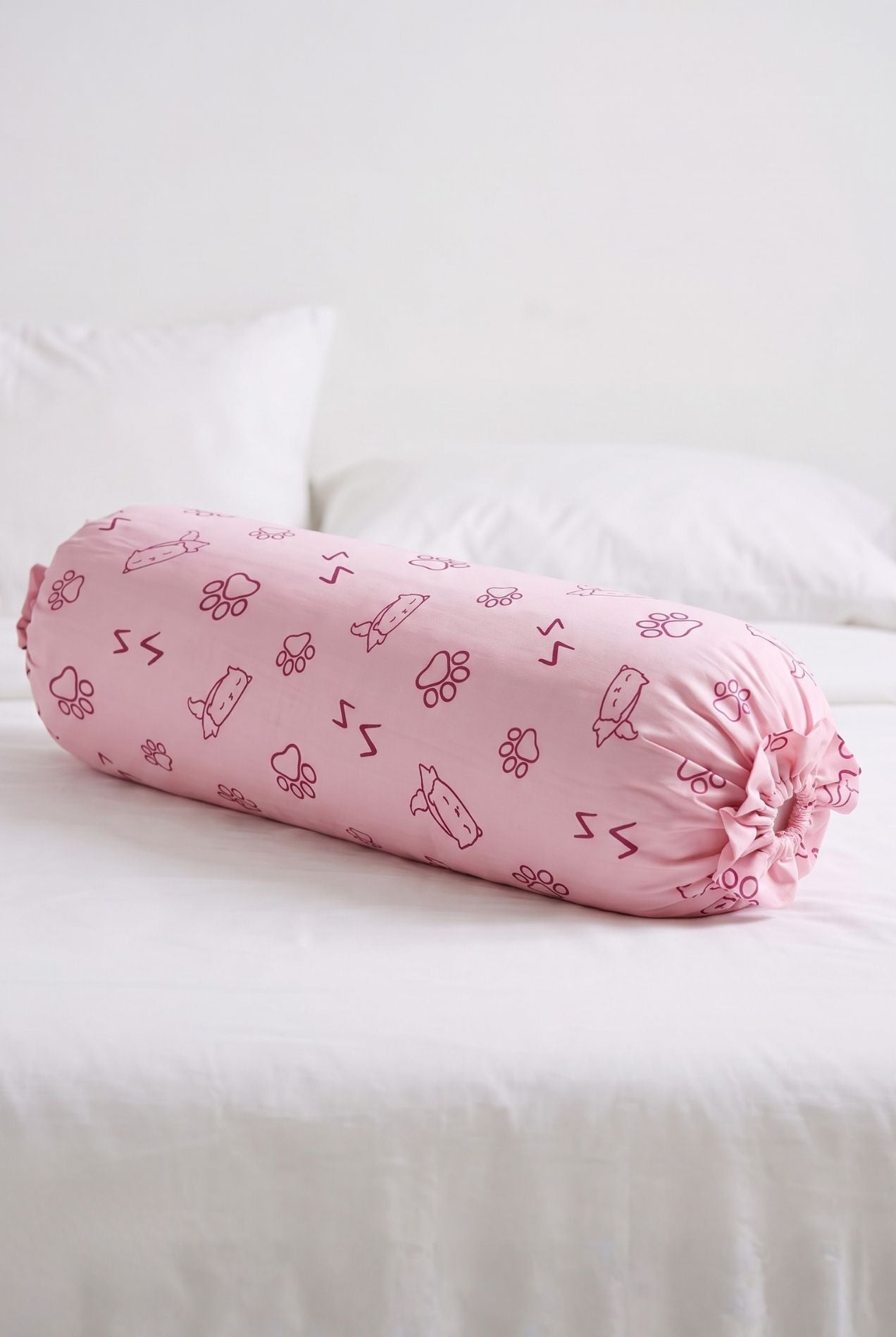 Paws & Snooze bamboo bolster cover in pink cat and paw print styled on a bed