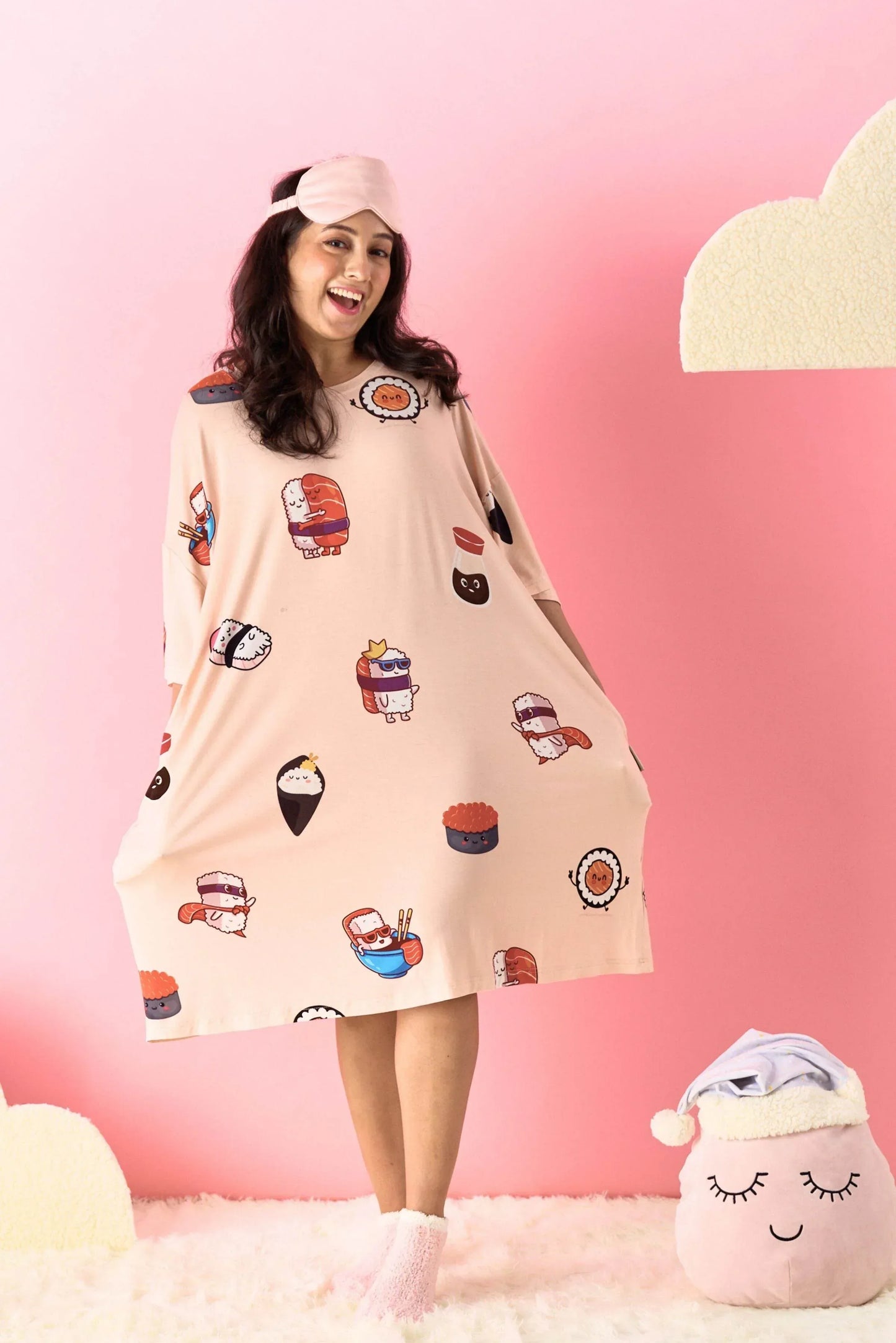 Woman wearing a patterned dress with cartoon sushi designs against a pink background